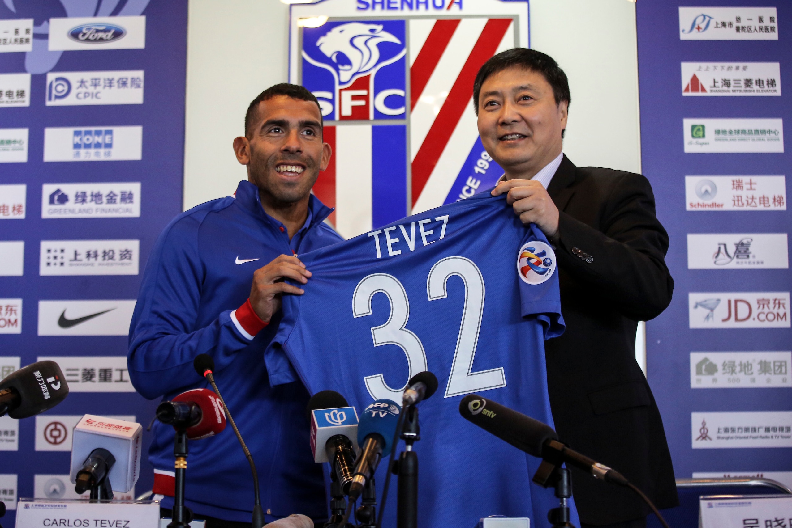 Argentine striker Carlos Tevez (L) poses with a jersey of his new club Shanghai Shenhua during a press conference in Shanghai on January 21, 2017.
Tevez held his first press conference for his new club Shanghai Shenhua, which reportedly has made him the w Argentine striker Carlos Tevez (L) poses with a jersey of his new club Shanghai Shenhua during a press conference in Shanghai on January 21, 2017.
Tevez held his first press conference for his new club Shanghai Shenhua, which reportedly has made him the w