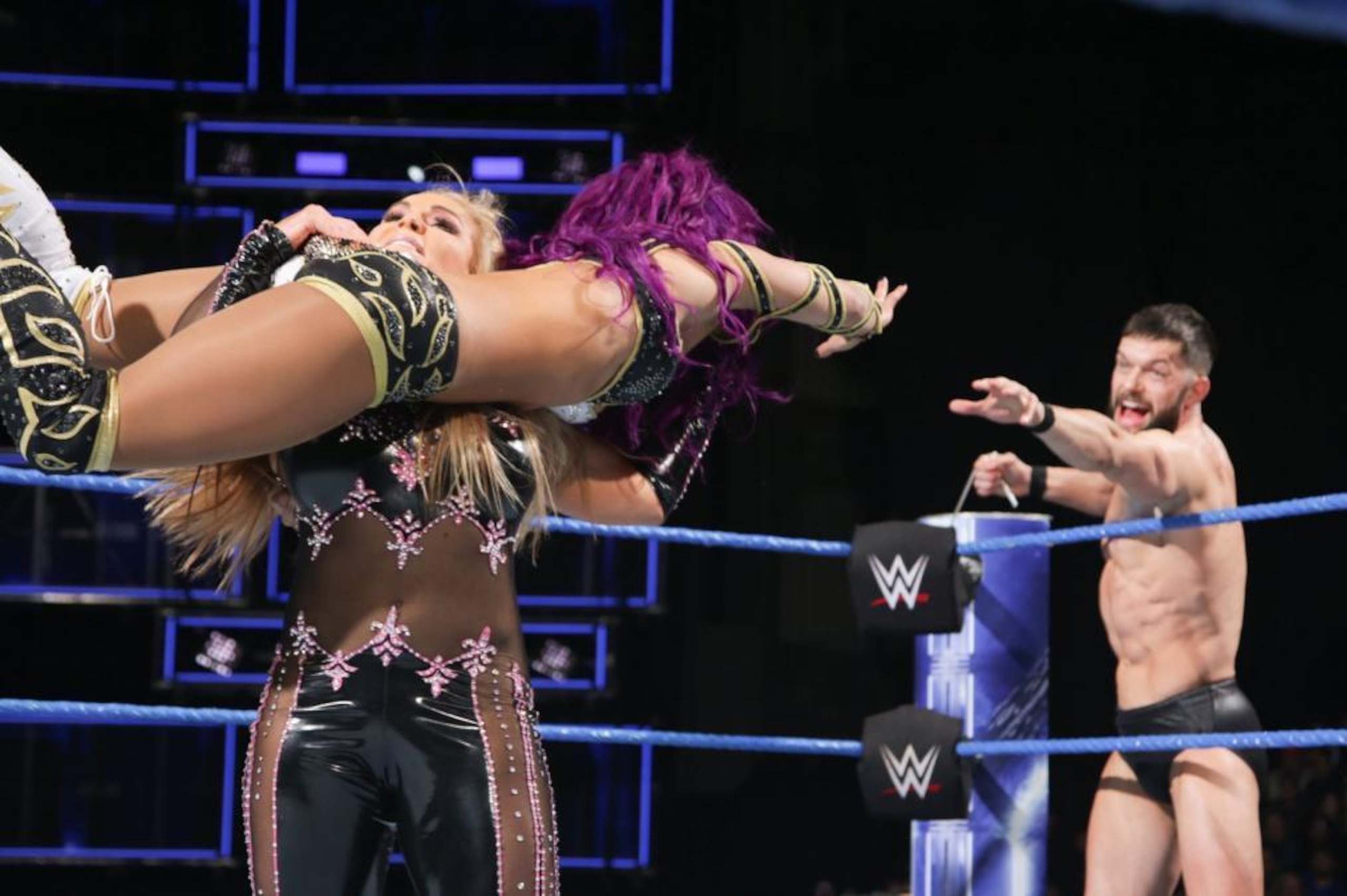 Sasha Banks looks to escape Natalya's grip and tag in Finn Balor.