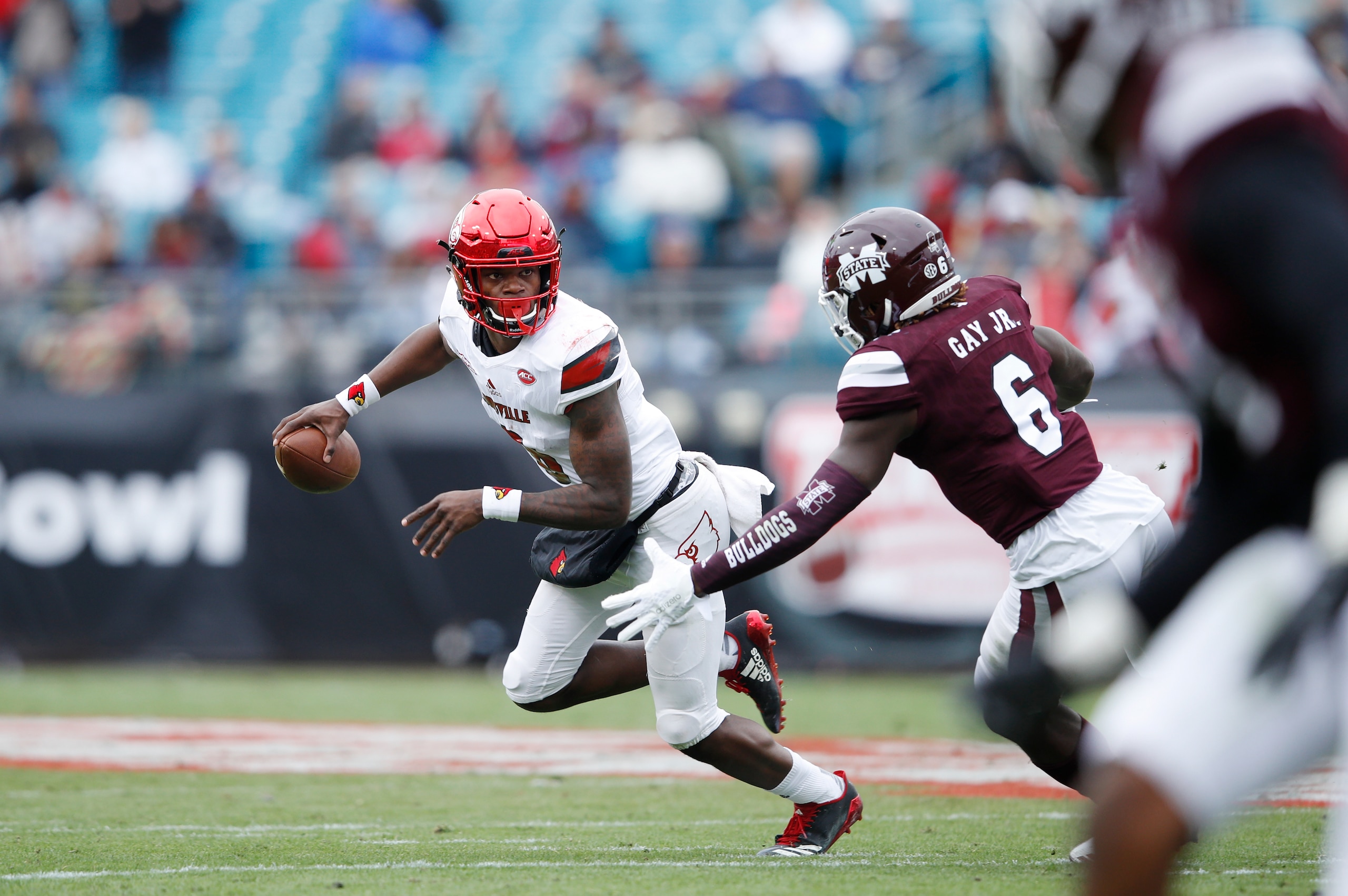 JACKSONVILLE, FL - DECEMBER 30: Lamar Jackson #8 of the Louisville Cardinals looks to pass while under pressure from Willie Gay Jr. #6 of the Mississippi State Bulldogs during the TaxSlayer Bowl at EverBank Field on December 30, 2017 in Jacksonville, Flor