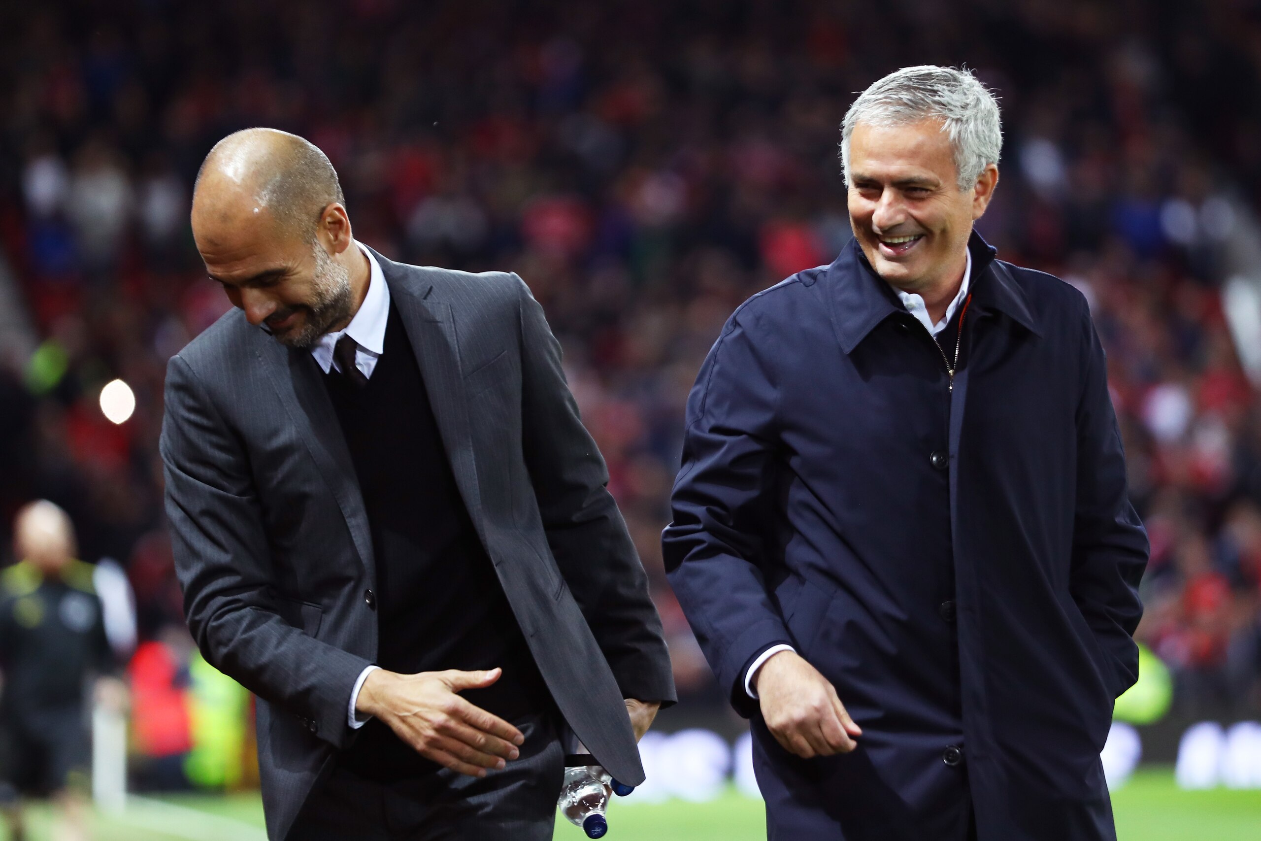 MANCHESTER, ENGLAND - OCTOBER 26: Josep Guardiola, Manager of Manchester City (L) and Jose Mourinho, Manager of Manchester United (R) share a joke prior to kick off during the EFL Cup fourth round match between Manchester United and Manchester City at Old