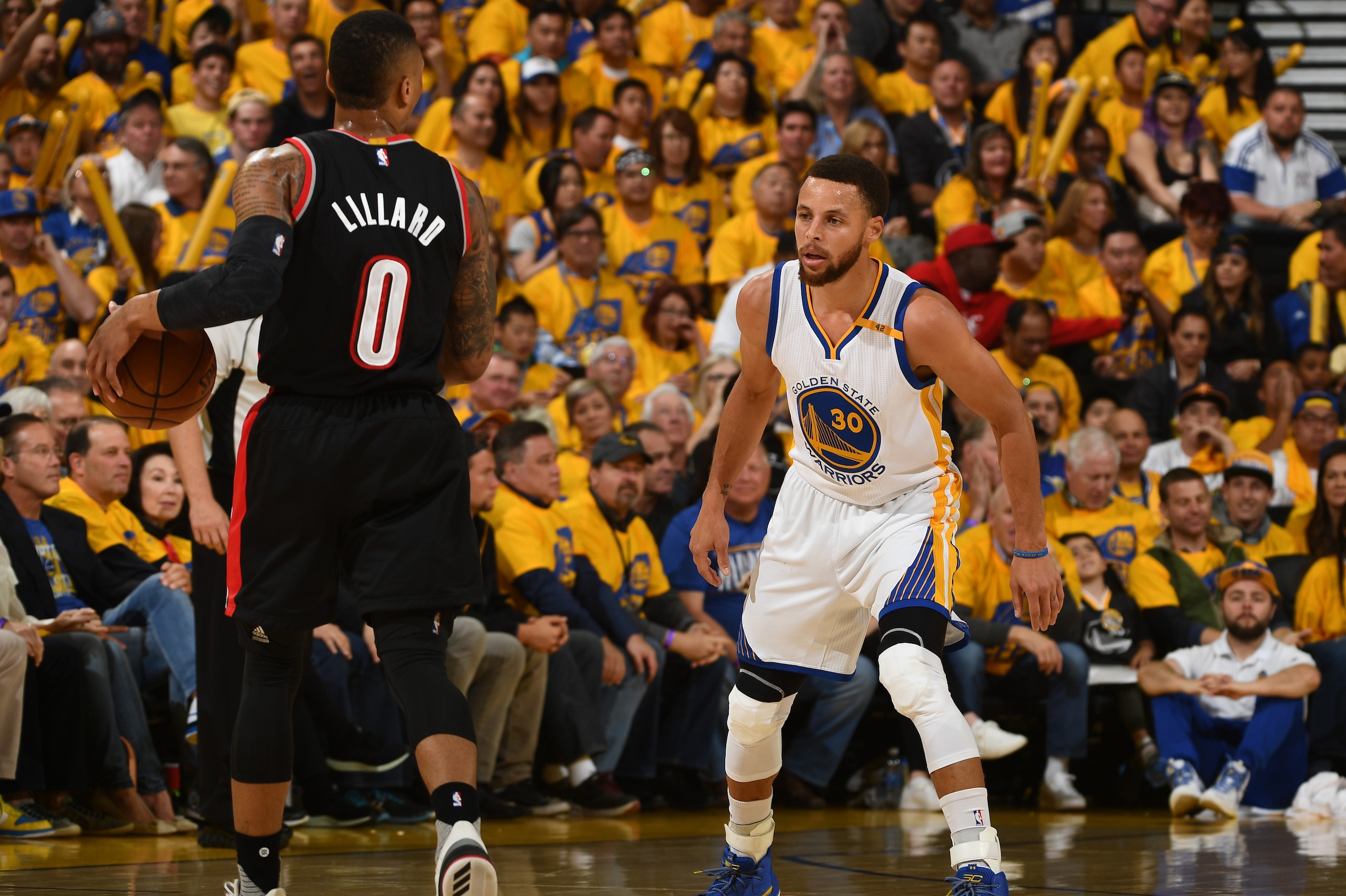 OAKLAND, CA - APRIL 16:  Damian Lillard #0 of the Portland Trail Blazers dribbles the ball while guarded by  Stephen Curry #30 of the Golden State Warriors during the Western Conference Quarterfinals game during the 2017 NBA Playoffs on April 16, 2017 at 
