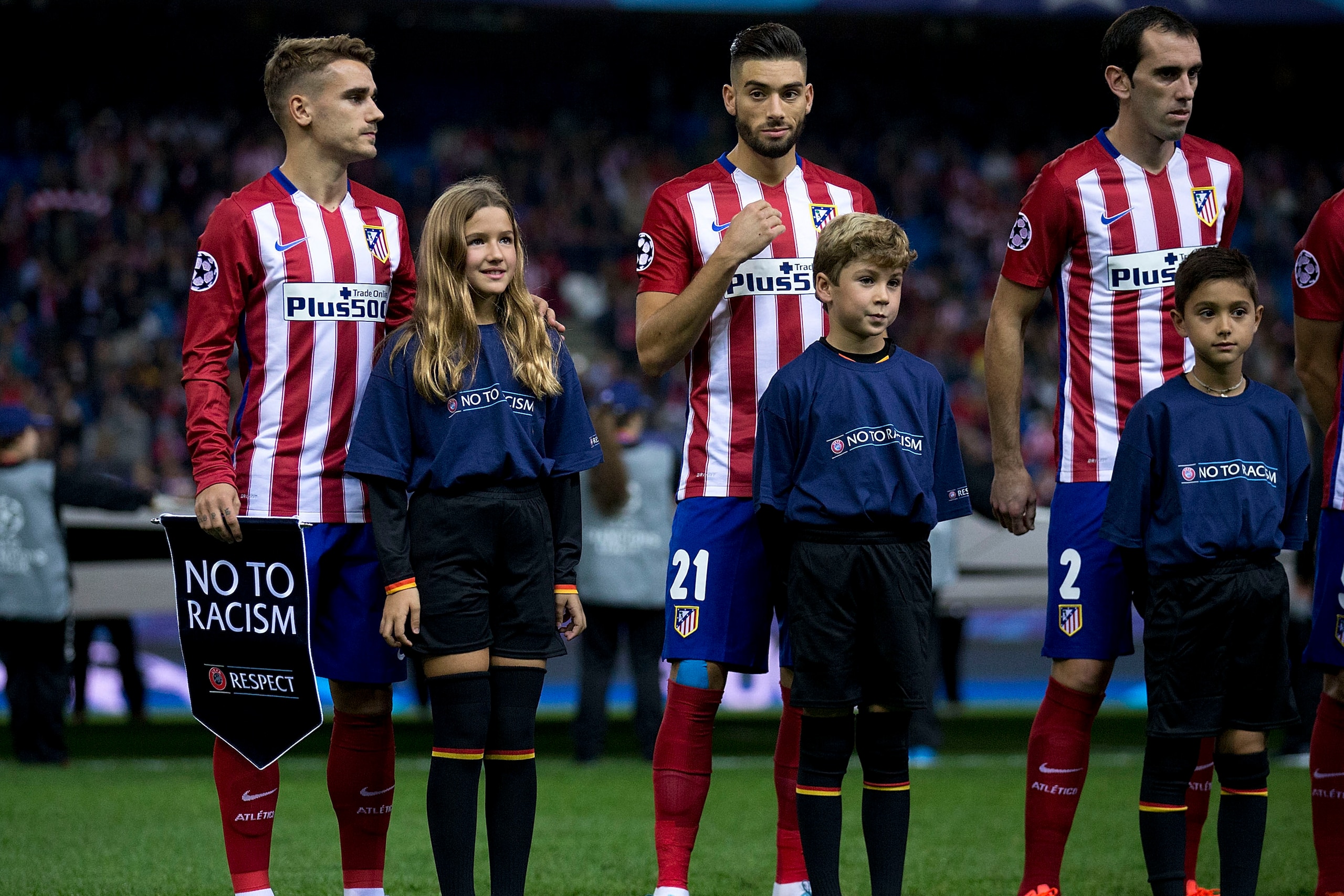 MADRID, SPAIN - OCTOBER 21:  Antoine Griezmann (L) of Atletico de Madrid holds the UEFA No To Racism pennant close to his teammates Yannick Carrasco (2ndL) and Juan Francisco Torres alias Juanfran (R) behind all of them behind the escort kids prior to sta