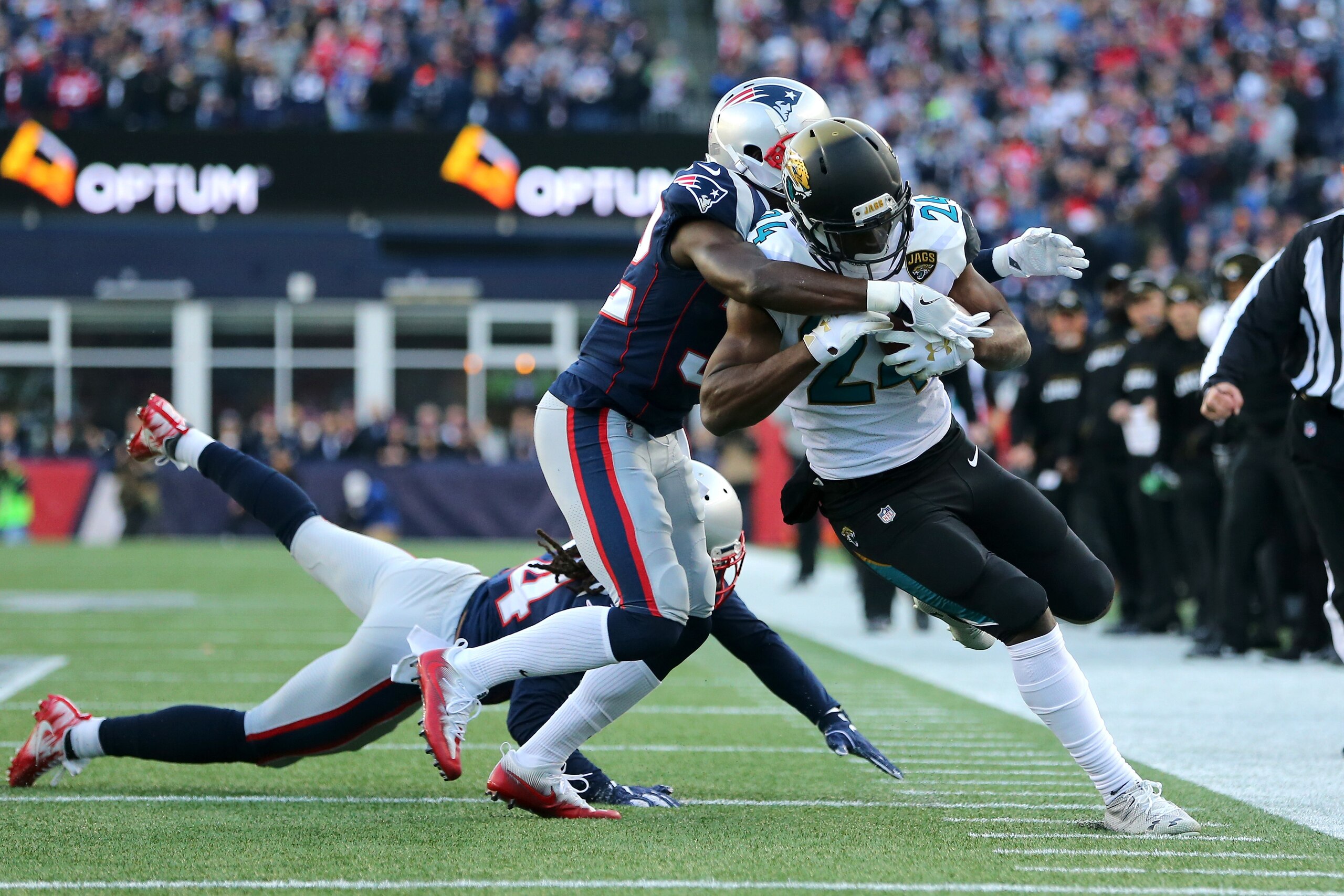 FOXBOROUGH, MA - JANUARY 21:  T.J. Yeldon #24 of the Jacksonville Jaguars carries the ball as he is defended by Patrick Chung #23 of the New England Patriots and Stephone Gilmore #24  in the first half  during the AFC Championship Game at Gillette Stadium