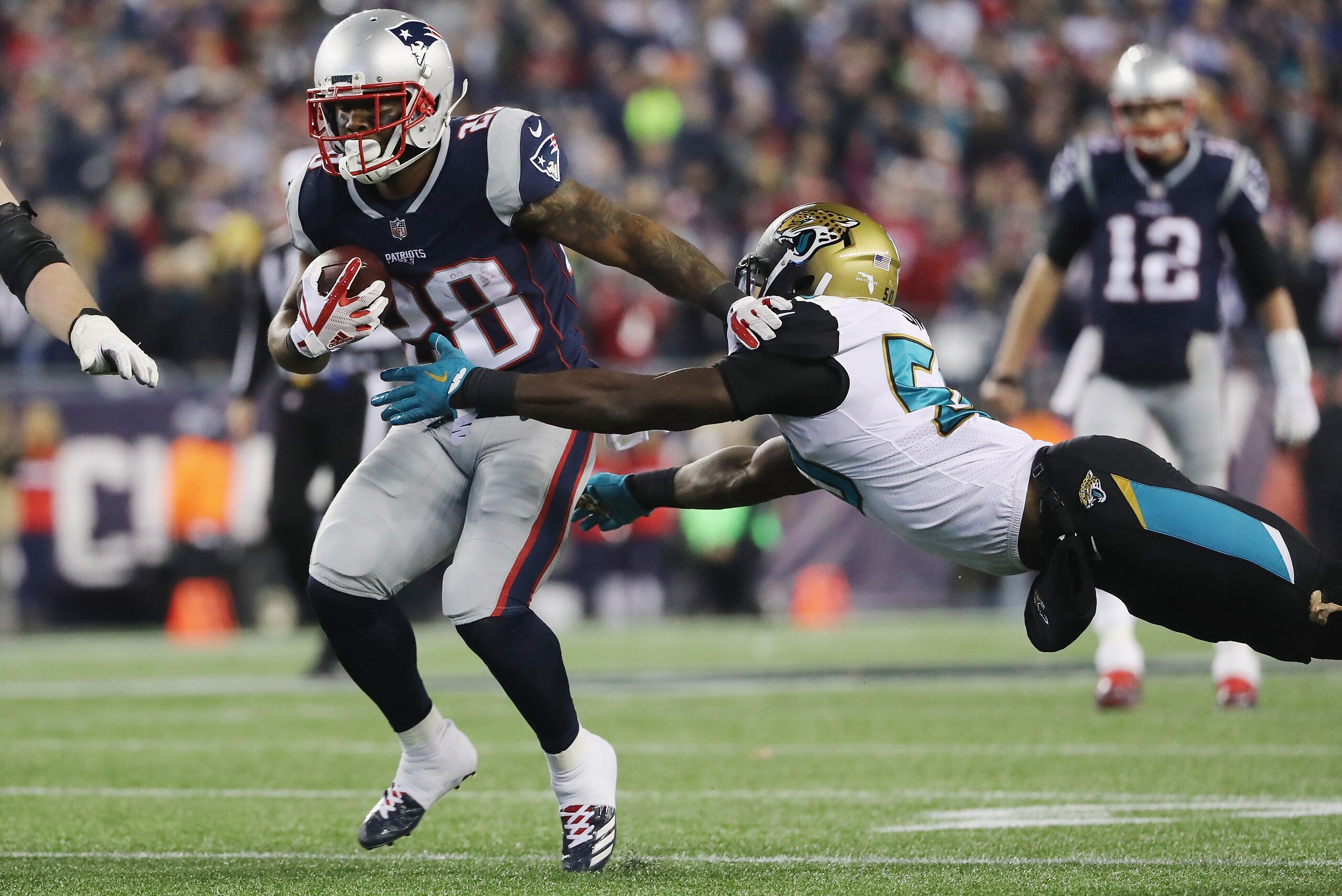 FOXBOROUGH, MA - JANUARY 21: James White #28 of the New England Patriots carries the ball as he is defended by Eli Ankou #54 of the Jacksonville Jaguars in the fourth quarter during the AFC Championship Game at Gillette Stadium on January 21, 2018 in Foxb