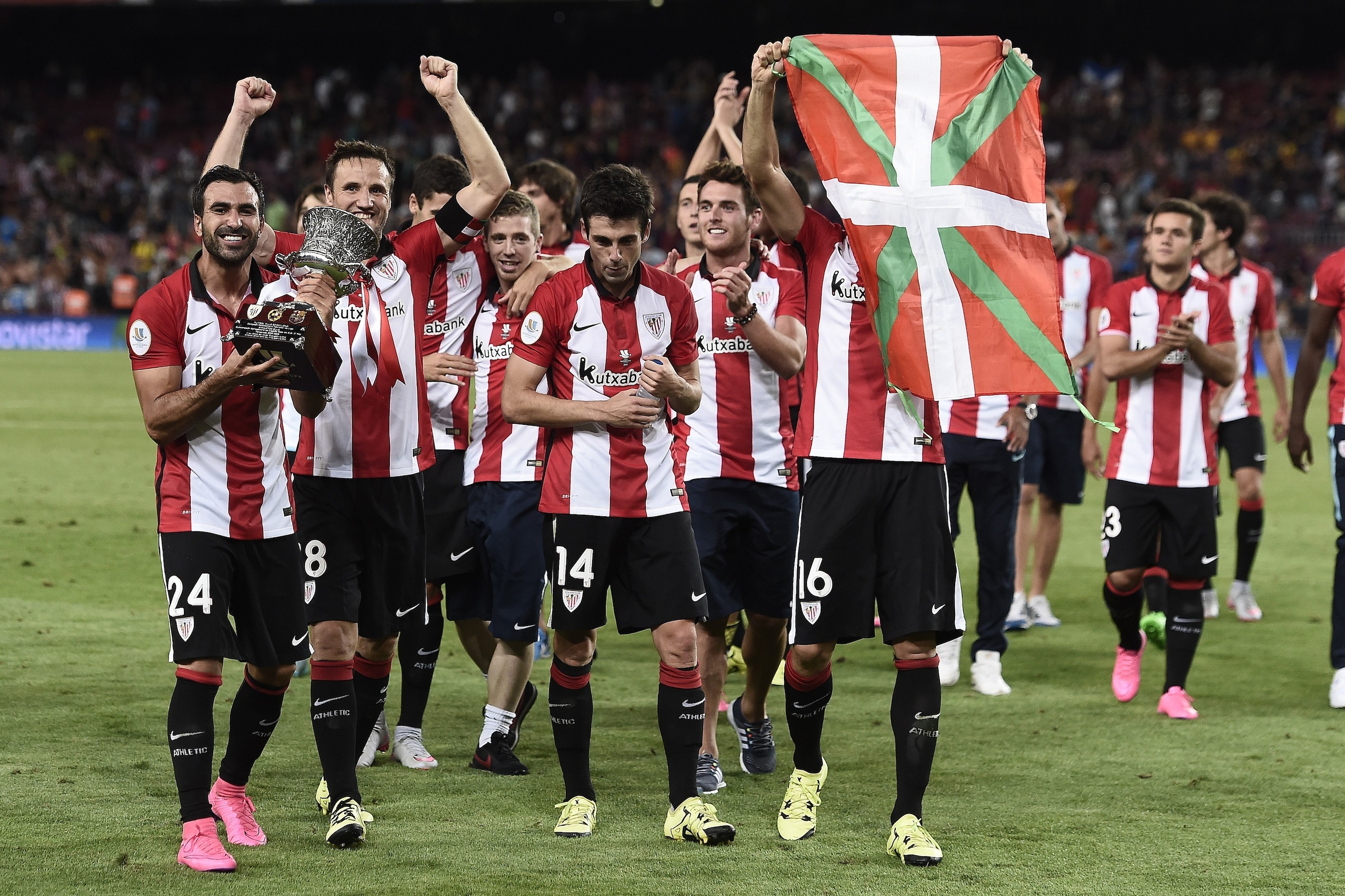 Athletic Bilbao's players wave an ikurrina (Basque flag) and hold their trophy as they celebrate after winning the the Spanish Supercup match during the Spanish Supercup second-leg football match FC Barcelona vs Athletic club Bilbao at the Camp Nou stadiu