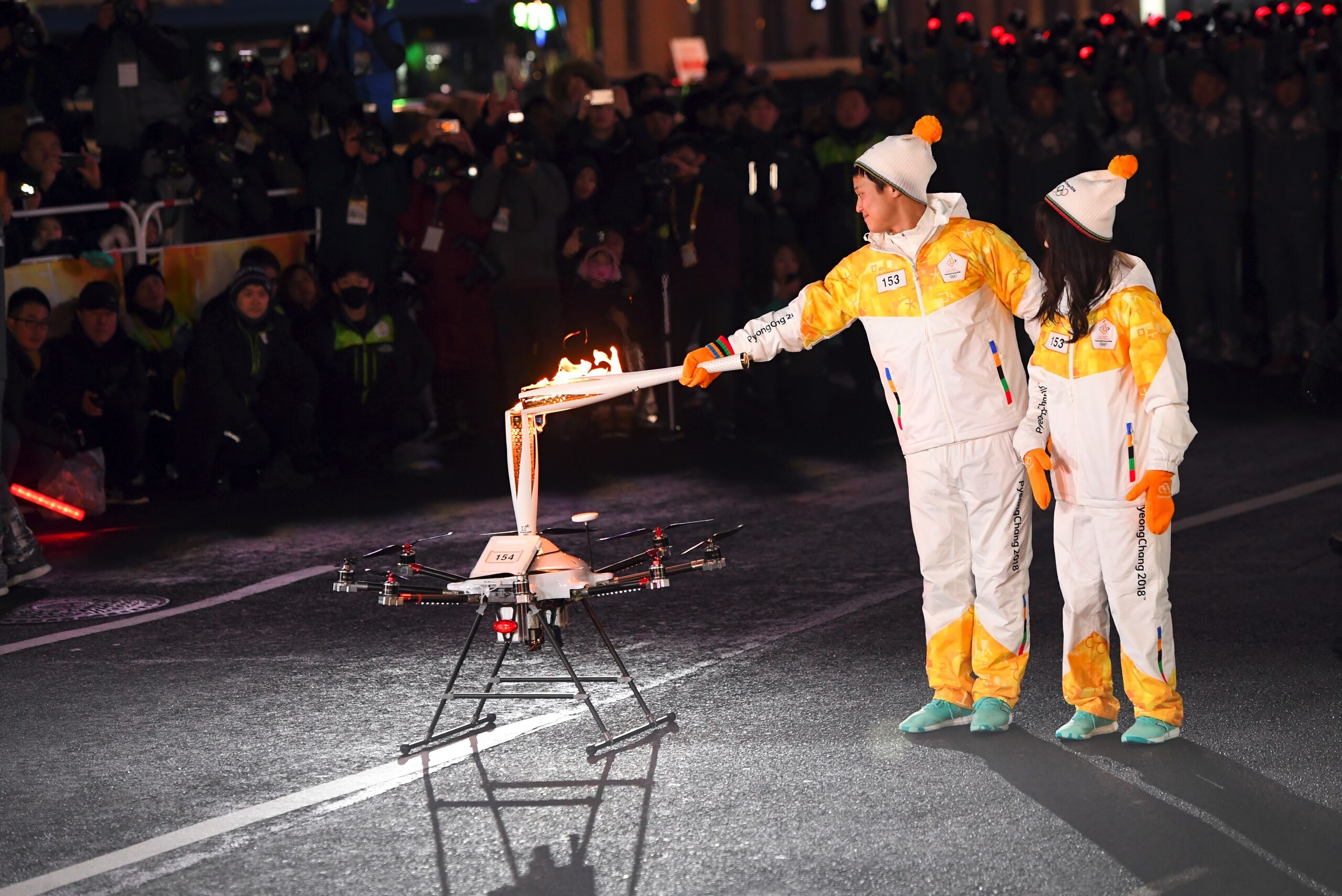Torchbearers pass the Olympic flame to a drone during the PyeongChang 2018 Torch Relay in Seoul on January 13, 2018.
Cheering crowds welcomed the Olympic flame to a freezing Seoul on January 13, where the torch will be paraded for four days before making Torchbearers pass the Olympic flame to a drone during the PyeongChang 2018 Torch Relay in Seoul on January 13, 2018.
Cheering crowds welcomed the Olympic flame to a freezing Seoul on January 13, where the torch will be paraded for four days before making