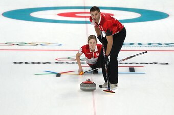 GANGNEUNG, SOUTH KOREA - FEBRUARY 09:  John Morris and Kaitlyn Lawes of Canada deliver a stone during the Curling Mixed Doubles Round Robin match ahead of the PyeongChang 2018 Winter Olympic Games at Gangneung Curling Centre on February 9, 2018 in Gangneu