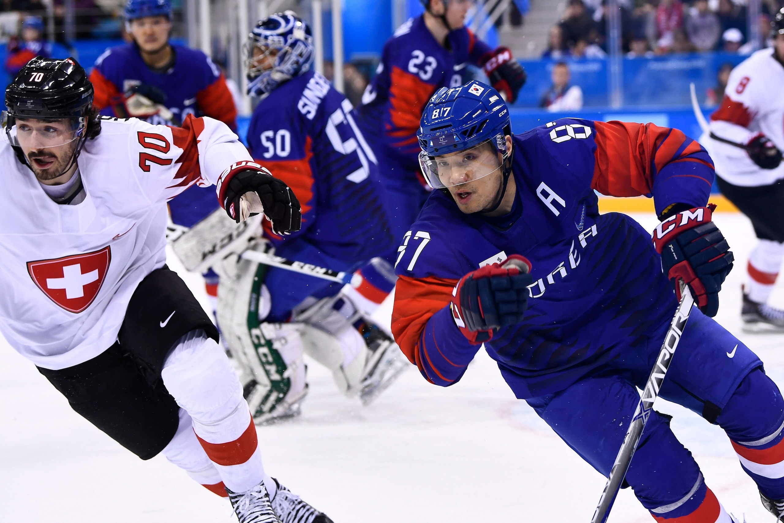 Switzerland's Denis Hollenstein (L) vies with South Korea's Minho Cho during the final period of a men's preliminary round ice hockey match between South Korea and Switzerland during the Pyeongchang 2018 Winter Olympic Games at the Gangneung Hockey Centre