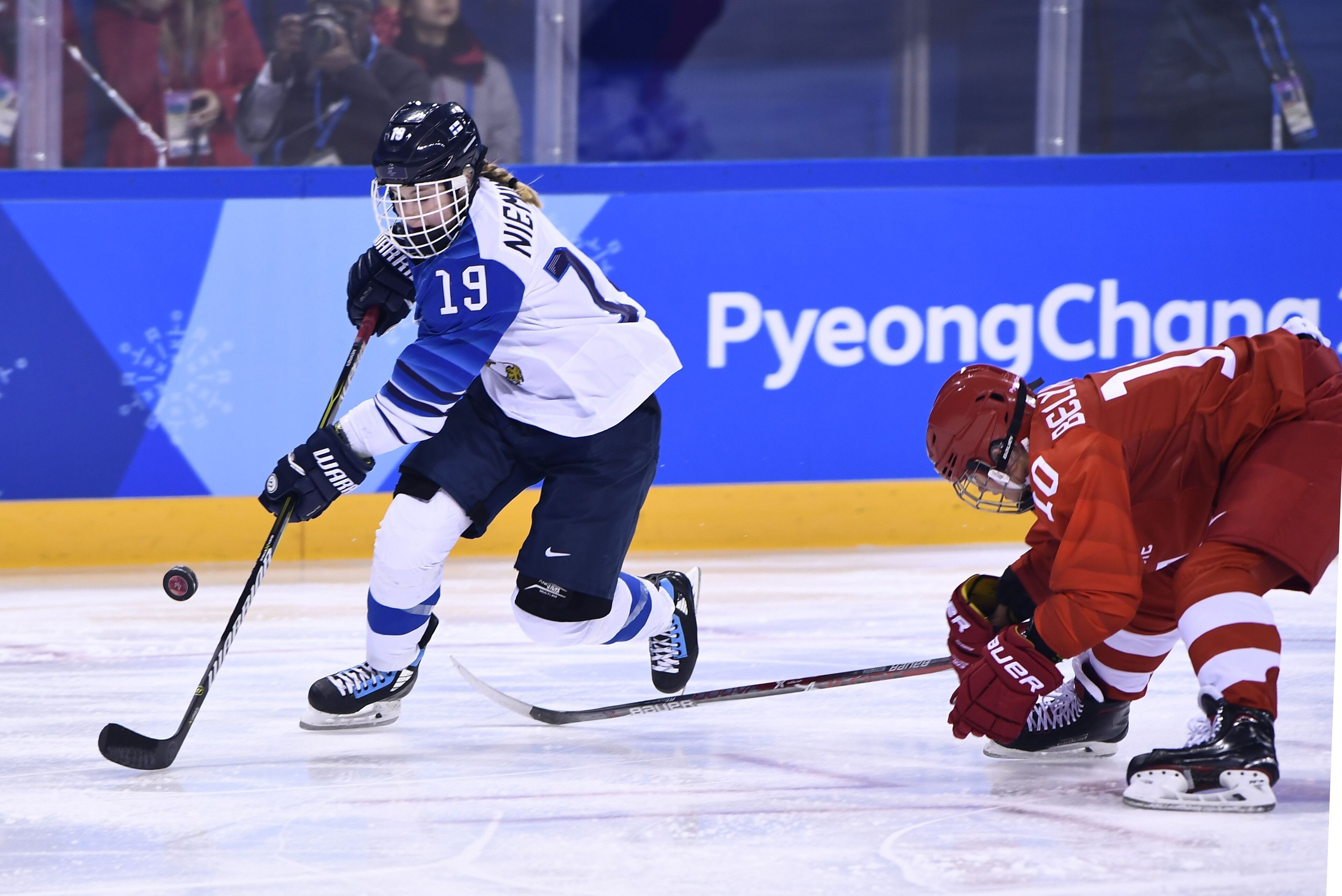 Finland's Petra Nieminen (L) controls the puck as Russia's Lyudmila Belyakova falls in the women's bronze medal ice hockey match between Finland and the Olympic Athletes  from Russia during the Pyeongchang 2018 Winter Olympic Games at the Kwandong Hockey 