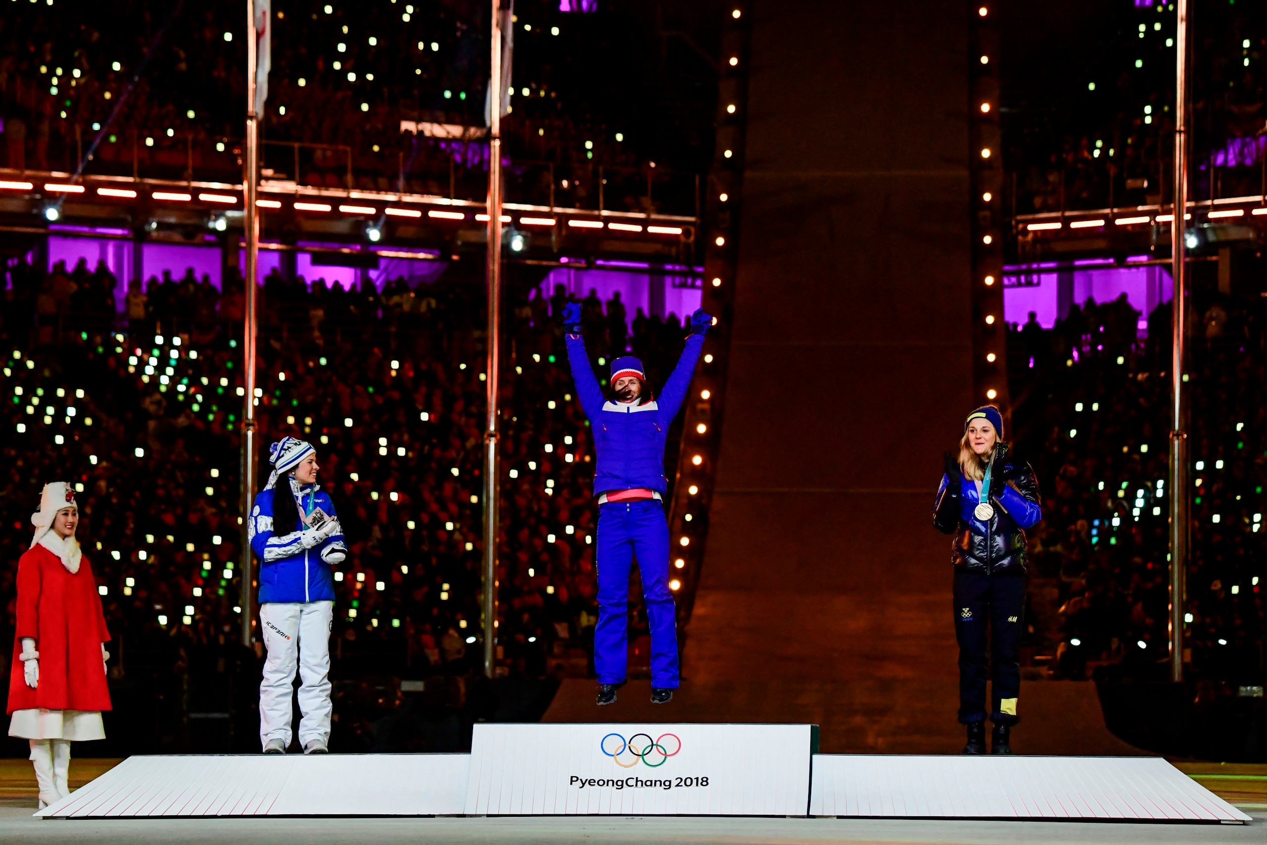 Finland's silver medallist Krista Parmakoski, Norway's gold medallist Marit Bjoergen and Sweden's bronze medallist Stina Nilsson celebrate on the podium during the medal ceremony for the cross country women's 30km mass start classic during the closing cer