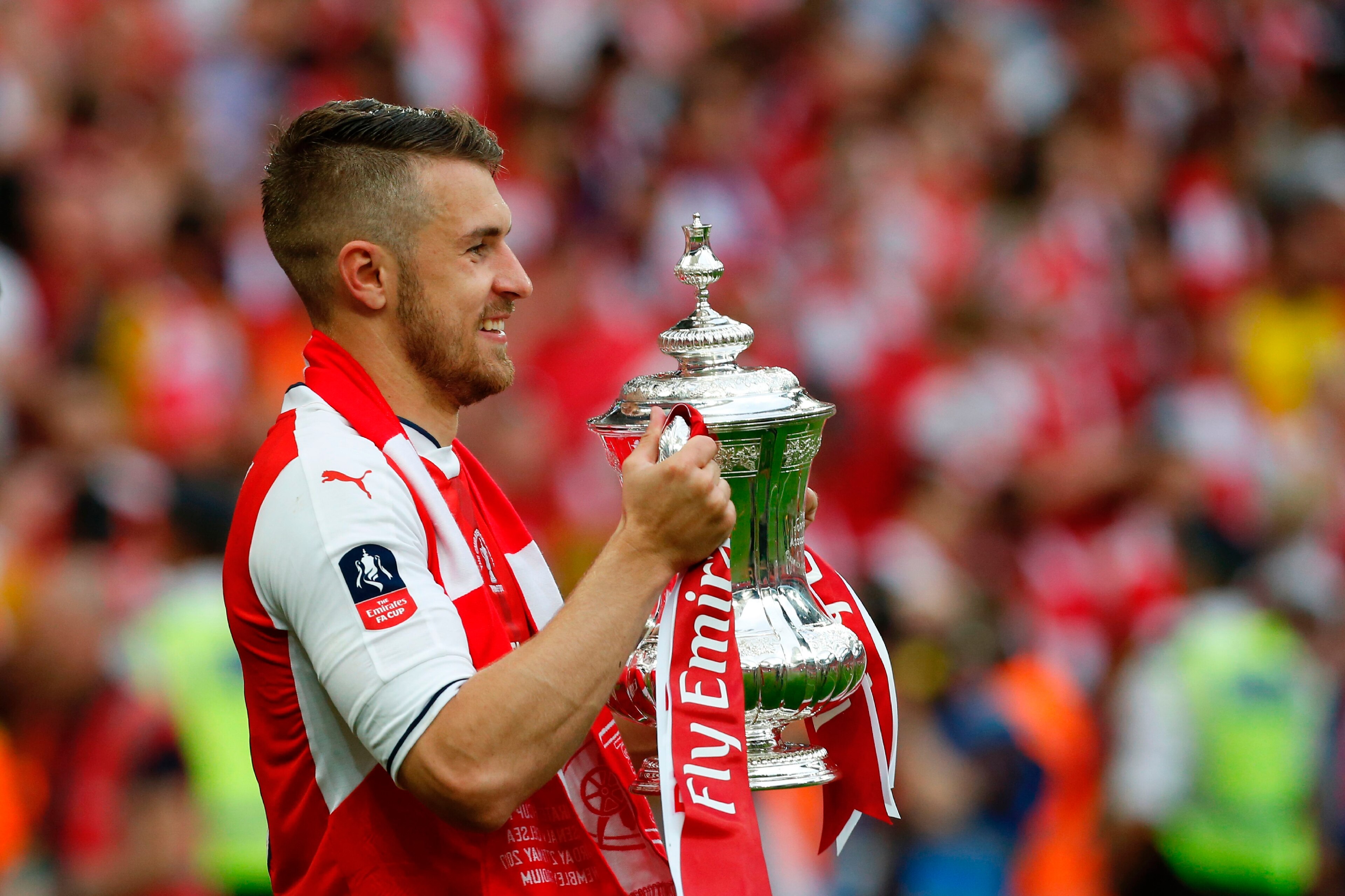 Arsenal's Welsh midfielder Aaron Ramsey holds the FA Cup trophy as Arsenal players celebrate their victory over Chelsea on the pitch after the English FA Cup final football match between Arsenal and Chelsea at Wembley stadium in London on May 27, 2017.
Aa