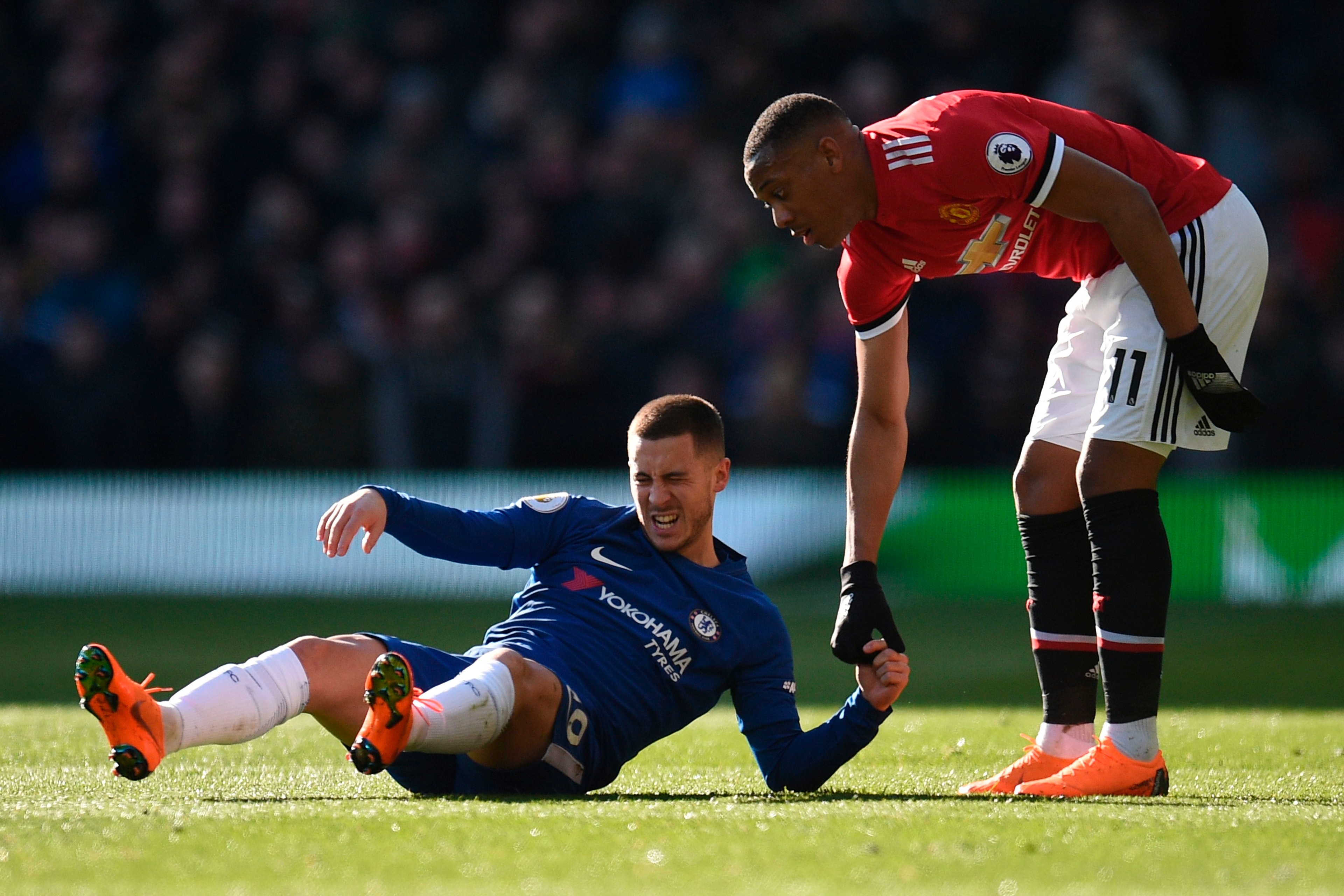 Manchester United's French striker Anthony Martial (R) helps up Chelsea's Belgian midfielder Eden Hazard (L) during the English Premier League football match between Manchester United and Chelsea at Old Trafford in Manchester, north west England, on Febru