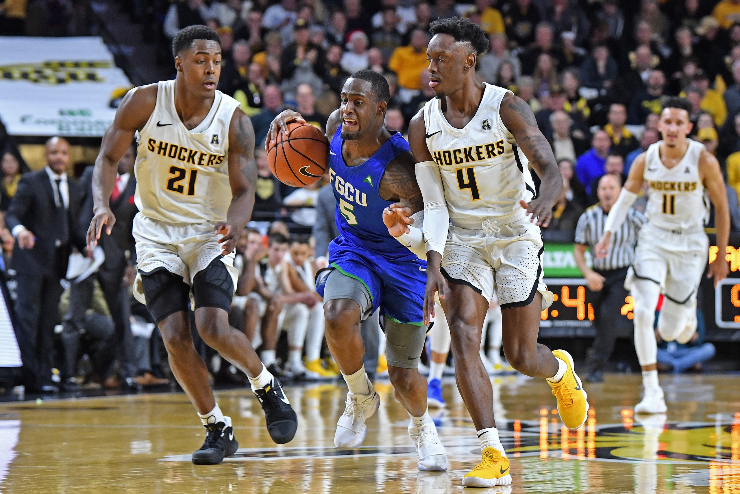 WICHITA, KS - DECEMBER 22:  Zach Johnson #5 of the Florida Gulf Coast Eagles drives up court against pressure from Samajae Haynes-Jones #4 and Darral Willis Jr. #21 of the Wichita State Shockers during the second half on December 22, 2017 at Charles Koch 