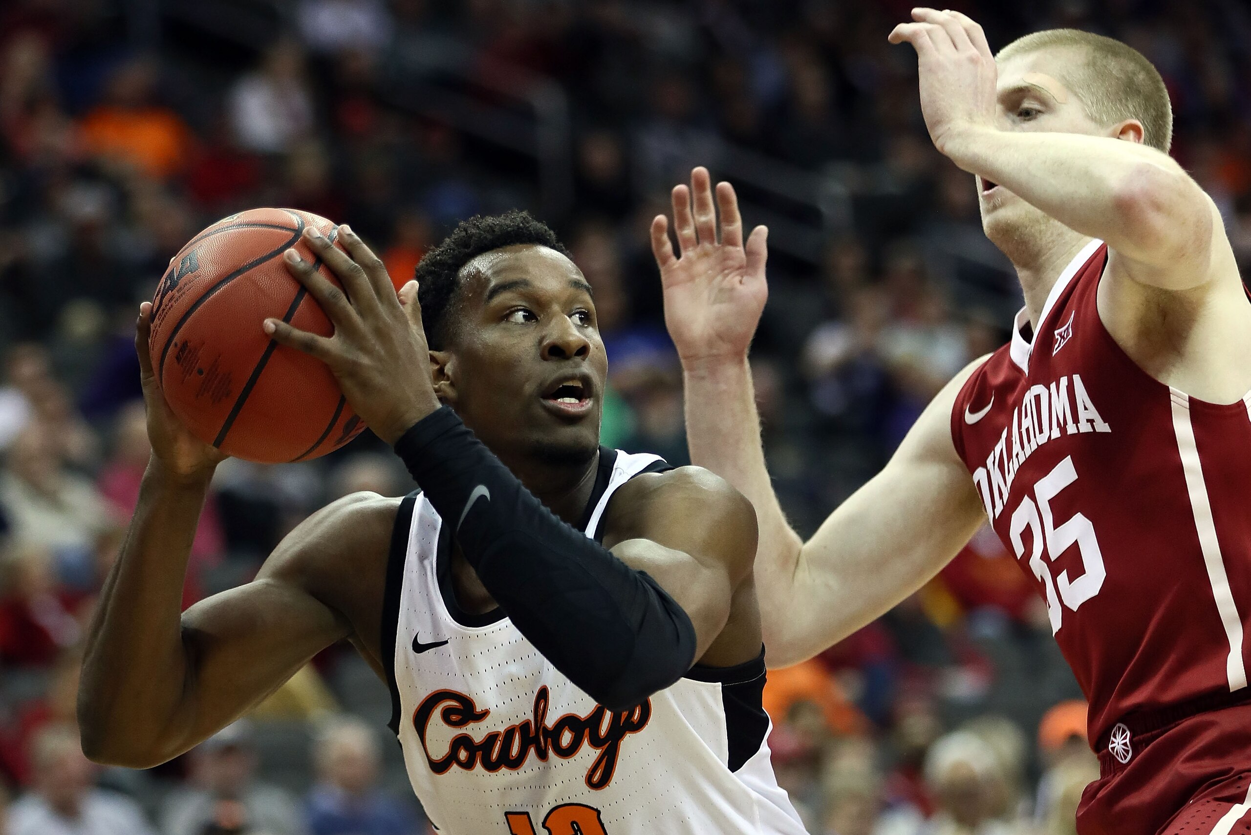 KANSAS CITY, MO - MARCH 07:  Cameron McGriff #12 of the Oklahoma State Cowboys controls the ball as Brady Manek #35 of the Oklahoma Sooners defends during the first round of the Big 12 Basketball Tournament at the Sprint Center on March 7, 2018 in Kansas 
