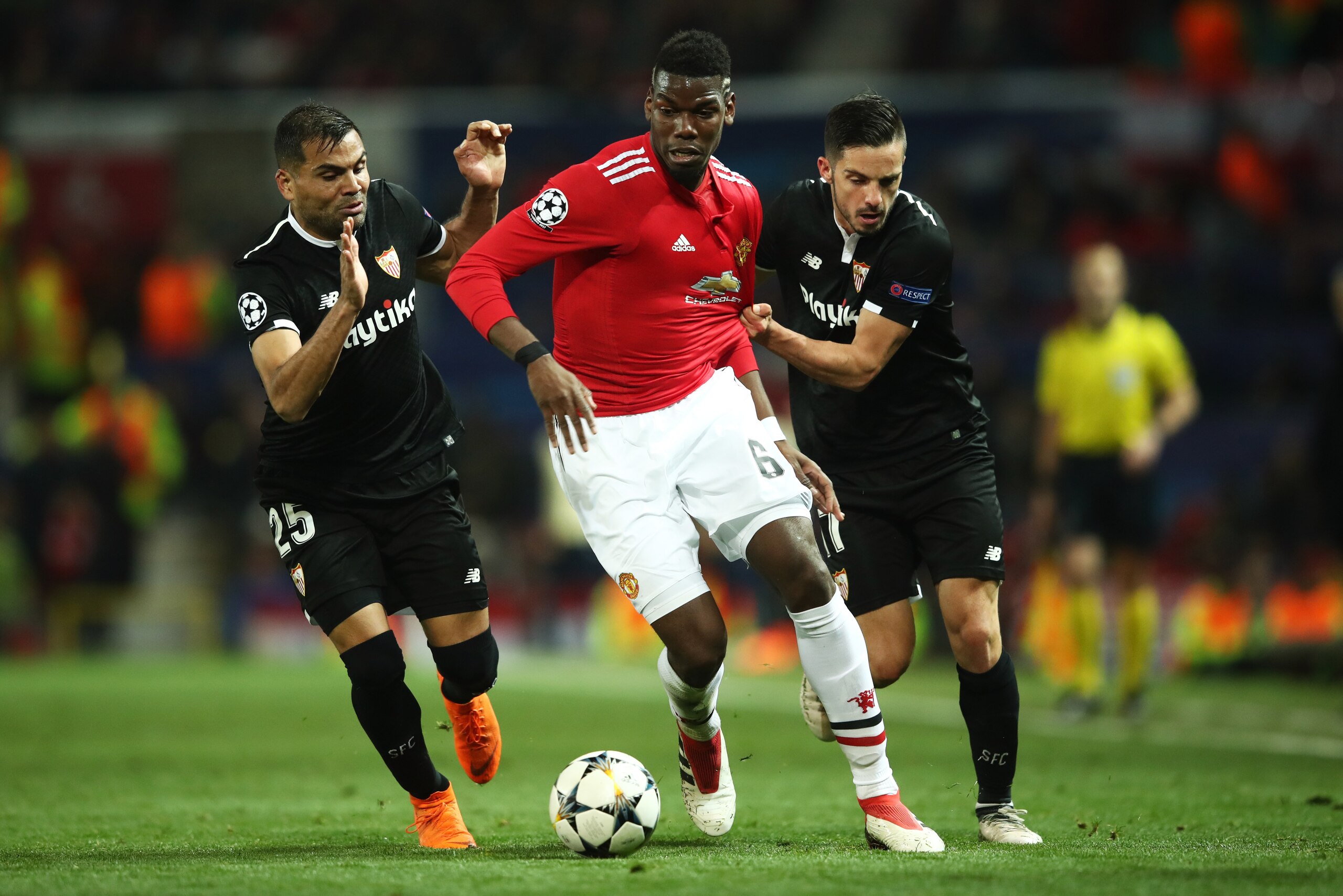 MANCHESTER, ENGLAND - MARCH 13:  Paul Pogba of Manchester United battles with Gabriel Mercado and Pablo Sarabia of Sevilla during the UEFA Champions League Round of 16 Second Leg match between Manchester United and Sevilla FC at Old Trafford on March 13, 