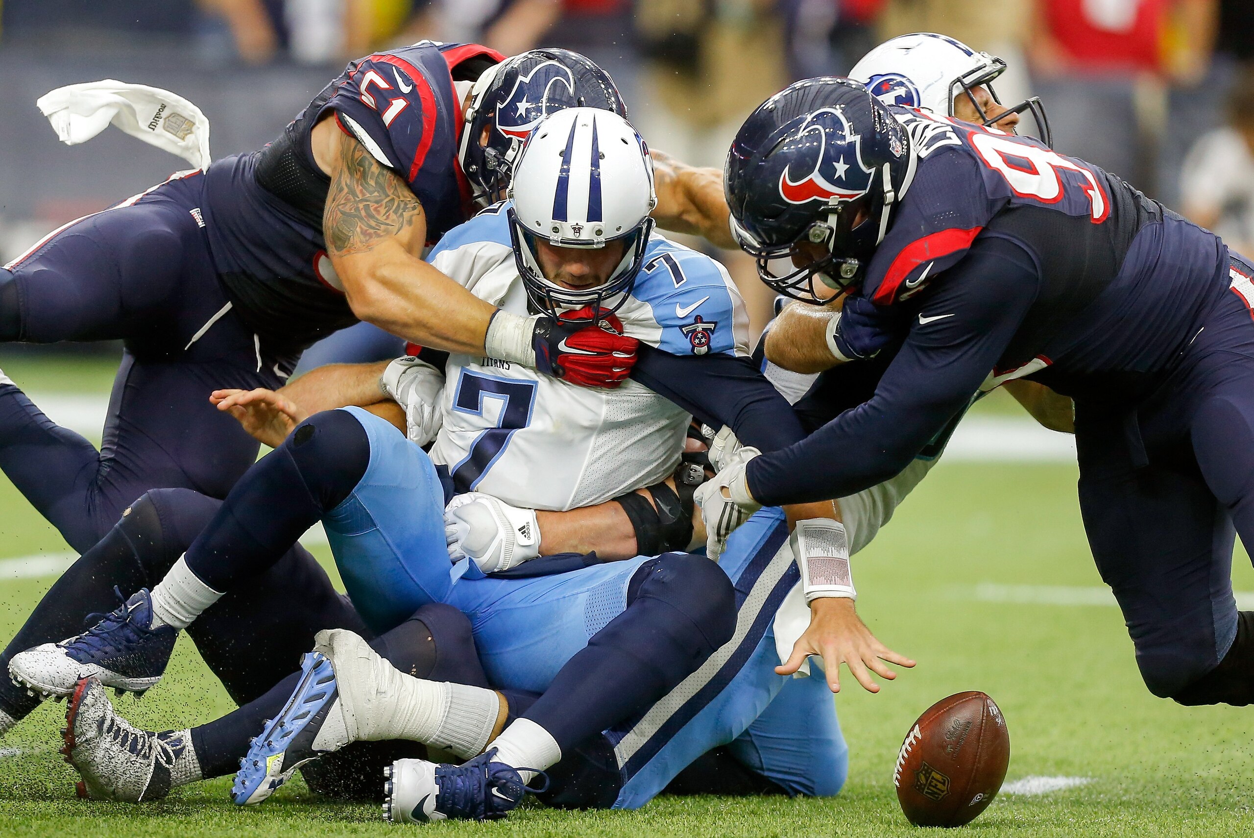 HOUSTON, TX - NOVEMBER 01:  Zach Mettenberger #7 of the Tennessee Titans fumbles the ball as he his hit by J.J. Watt #99 of the Houston Texans, Jadeveon Clowney #90 and John Simon at NRG Stadium on November 1, 2015 in Houston, Texas.  (Photo by Bob Levey/