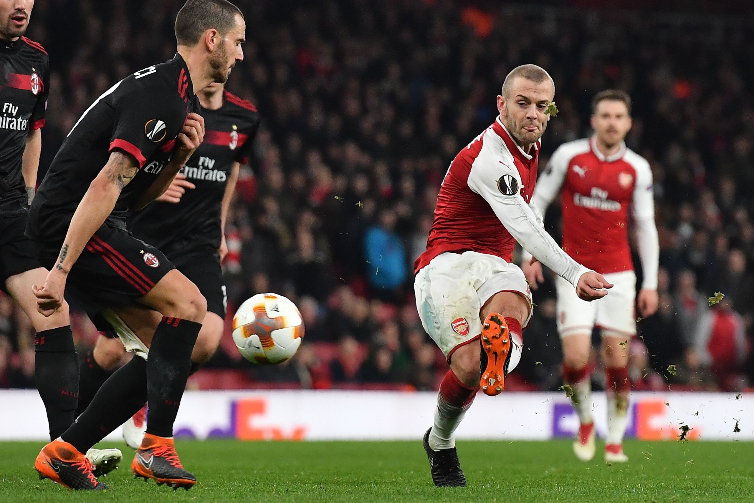 Arsenal's English midfielder Jack Wilshere (R) takes a shot during the UEFA Europa League round of 16 second-leg football match  between Arsenal and AC Milan at the Emirates Stadium in London on March 15, 2018.  / AFP PHOTO / Ben STANSALL        (Photo cr