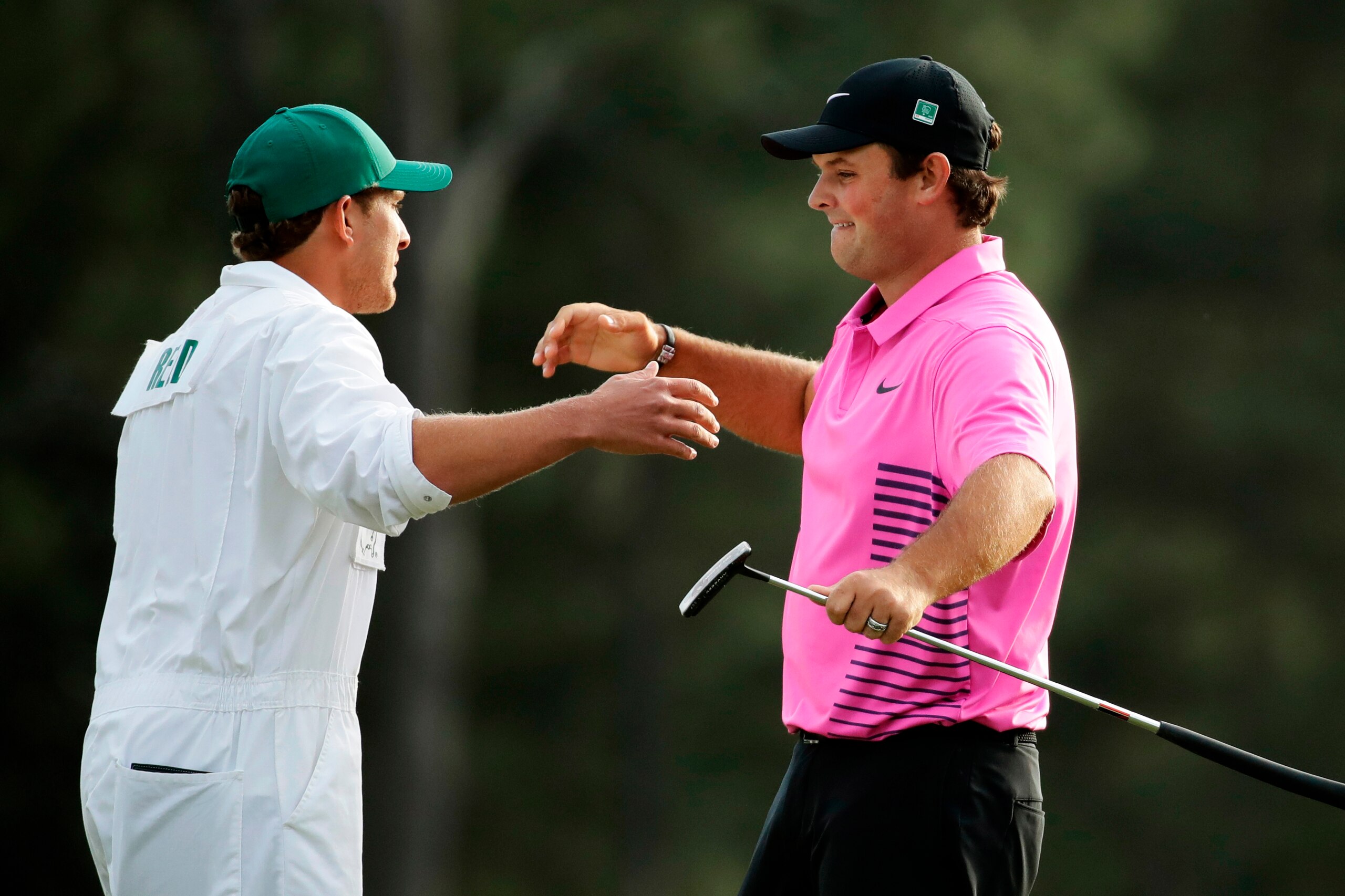 Reed celebrates with his caddy after sealing his win at Augusta on the 18th hole.