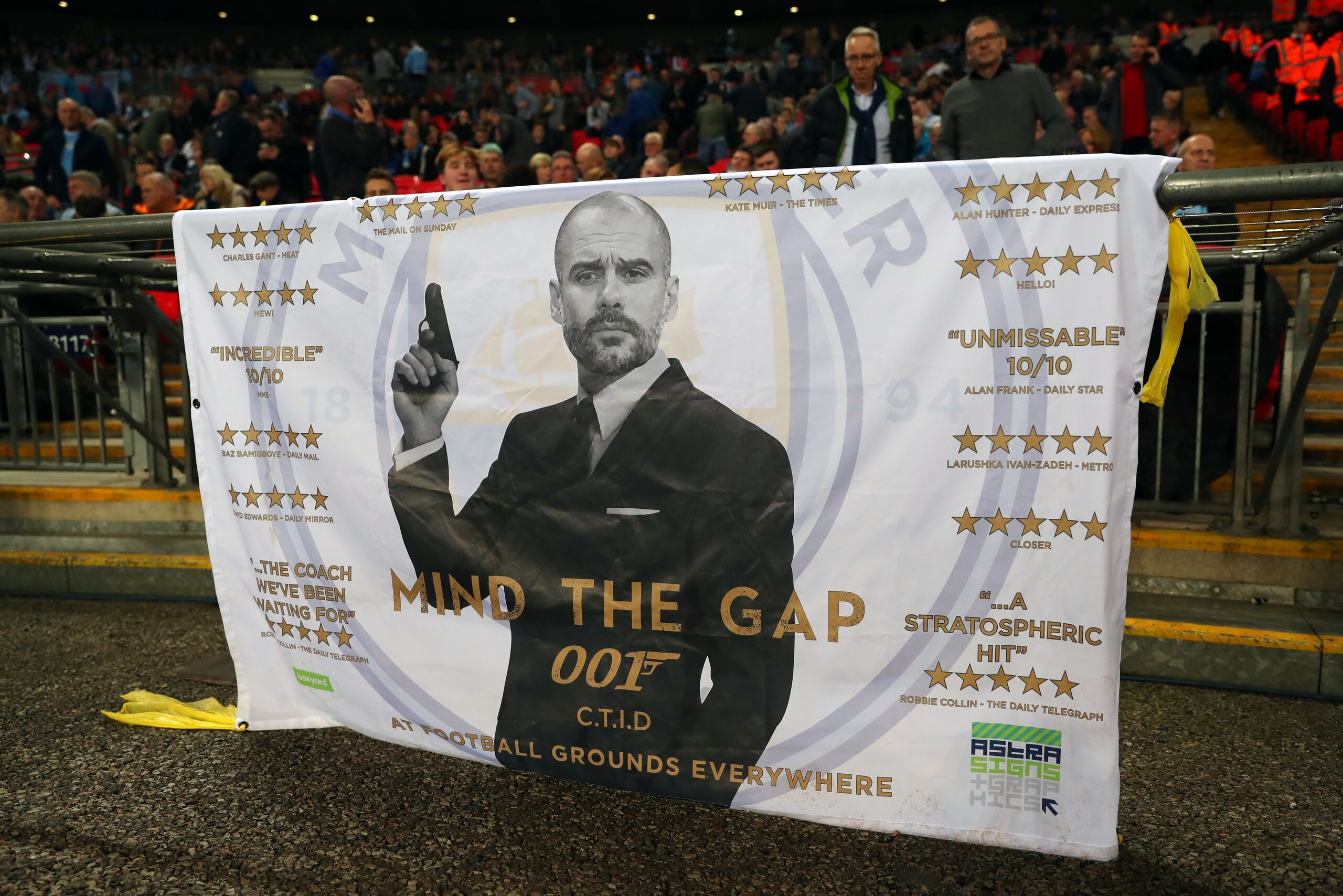 LONDON, ENGLAND - APRIL 14: A banner bearing a picture of Pep Guardiola the head coach / manager of Manchester City dressed as James Bond saying mind the gap during the Premier League match between Tottenham Hotspur and Manchester City at Wembley Stadium 