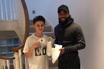 Sam Morgan hands over Alexander McQueen sneakers to Arsenal's Alexandre Lacazette.