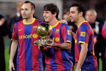 Barcelona's Argentinian forward Lionel Messi (C), flanked with Barcelona's midfielder Xavi Hernandez (R) and Barcelona's midfielder Andres Iniesta (L), poses with the 2010 Ballon d'Or trophy (Golden Ball) for the best European footballer of the year prior
