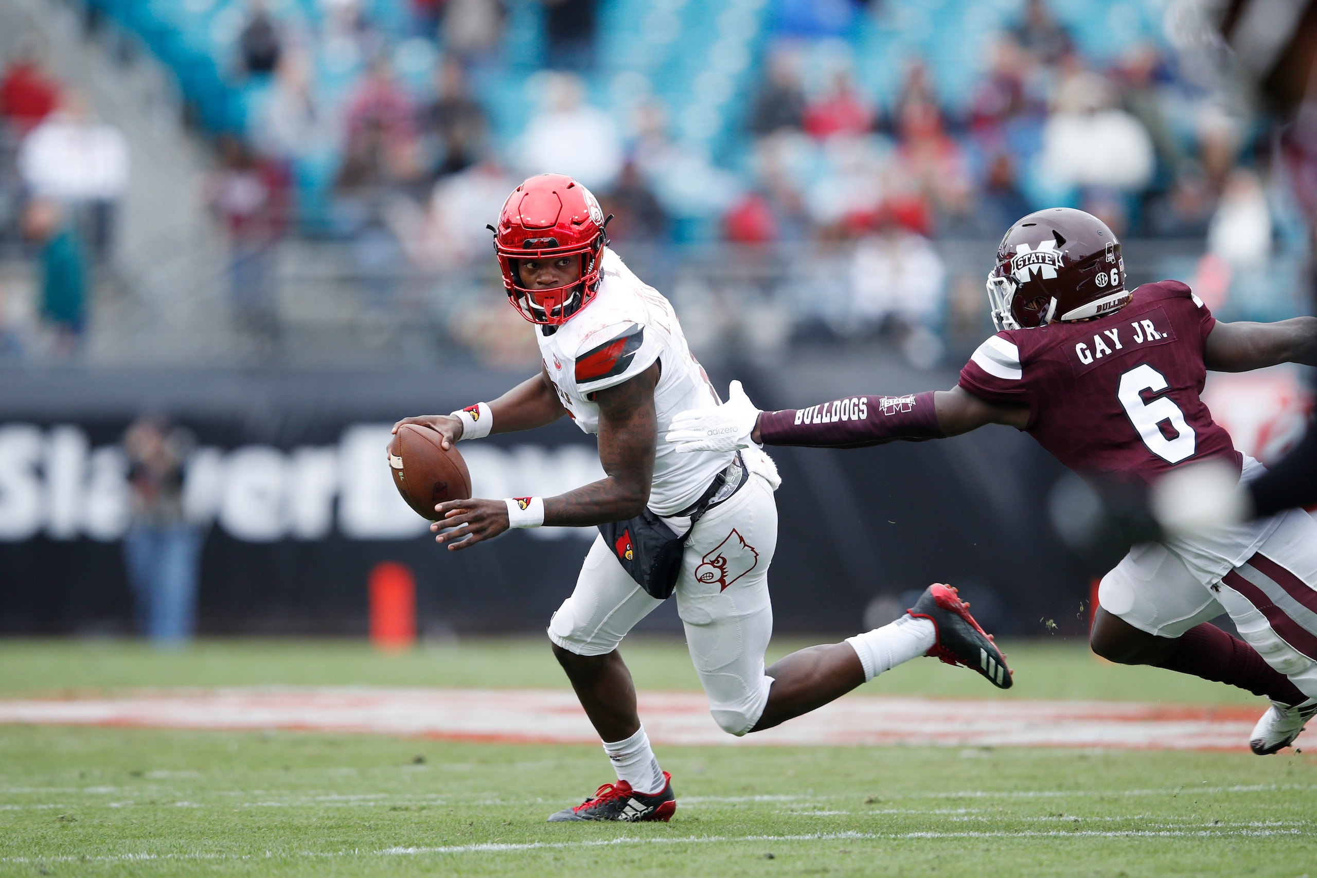 JACKSONVILLE, FL - DECEMBER 30: Lamar Jackson #8 of the Louisville Cardinals looks to pass while under pressure from Willie Gay Jr. #6 of the Mississippi State Bulldogs during the TaxSlayer Bowl at EverBank Field on December 30, 2017 in Jacksonville, Flor
