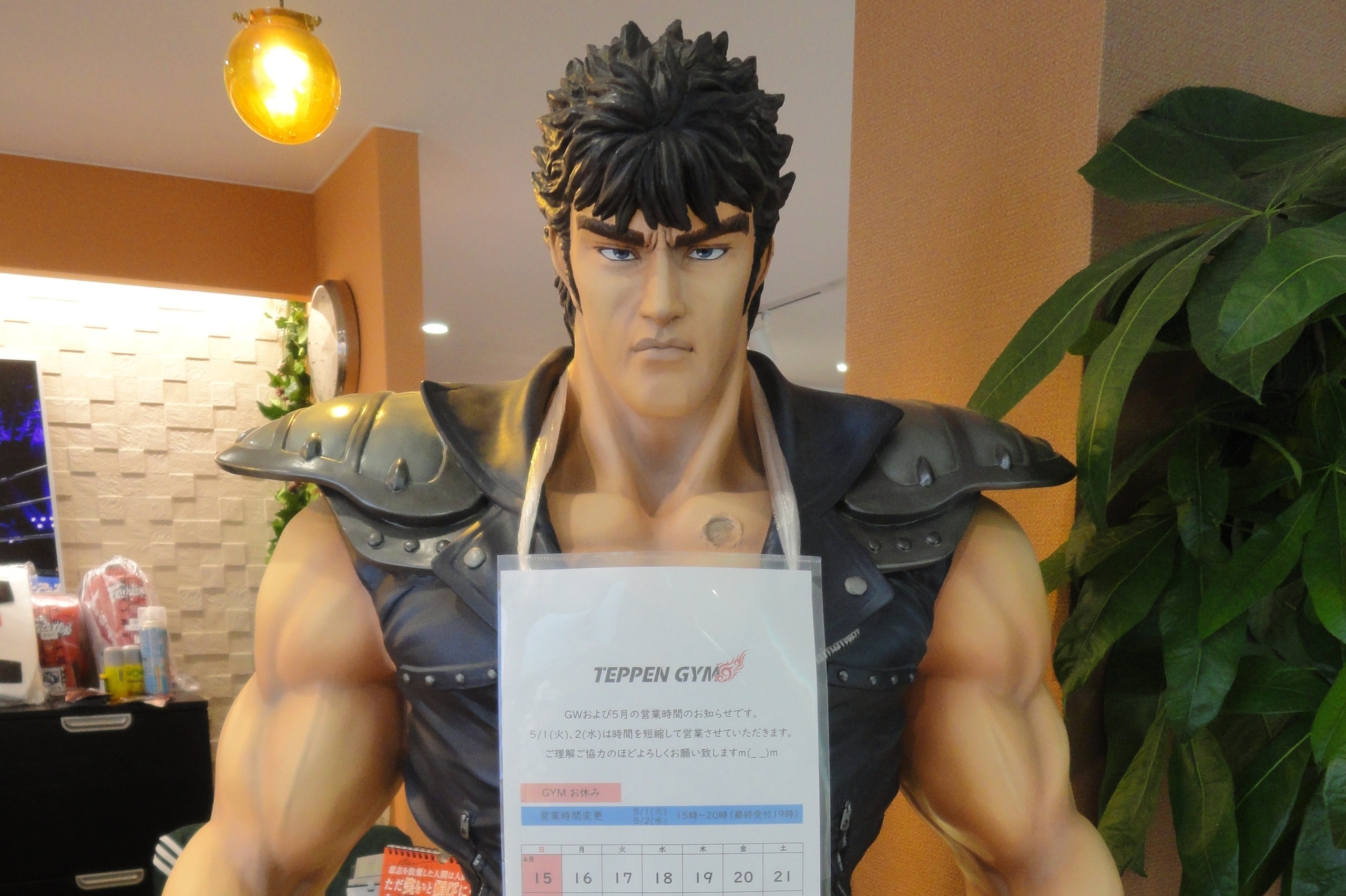 A statue of Kenshiro from 'Fist of the North Star' sits in the gym's entryway, displaying the schedule of events.