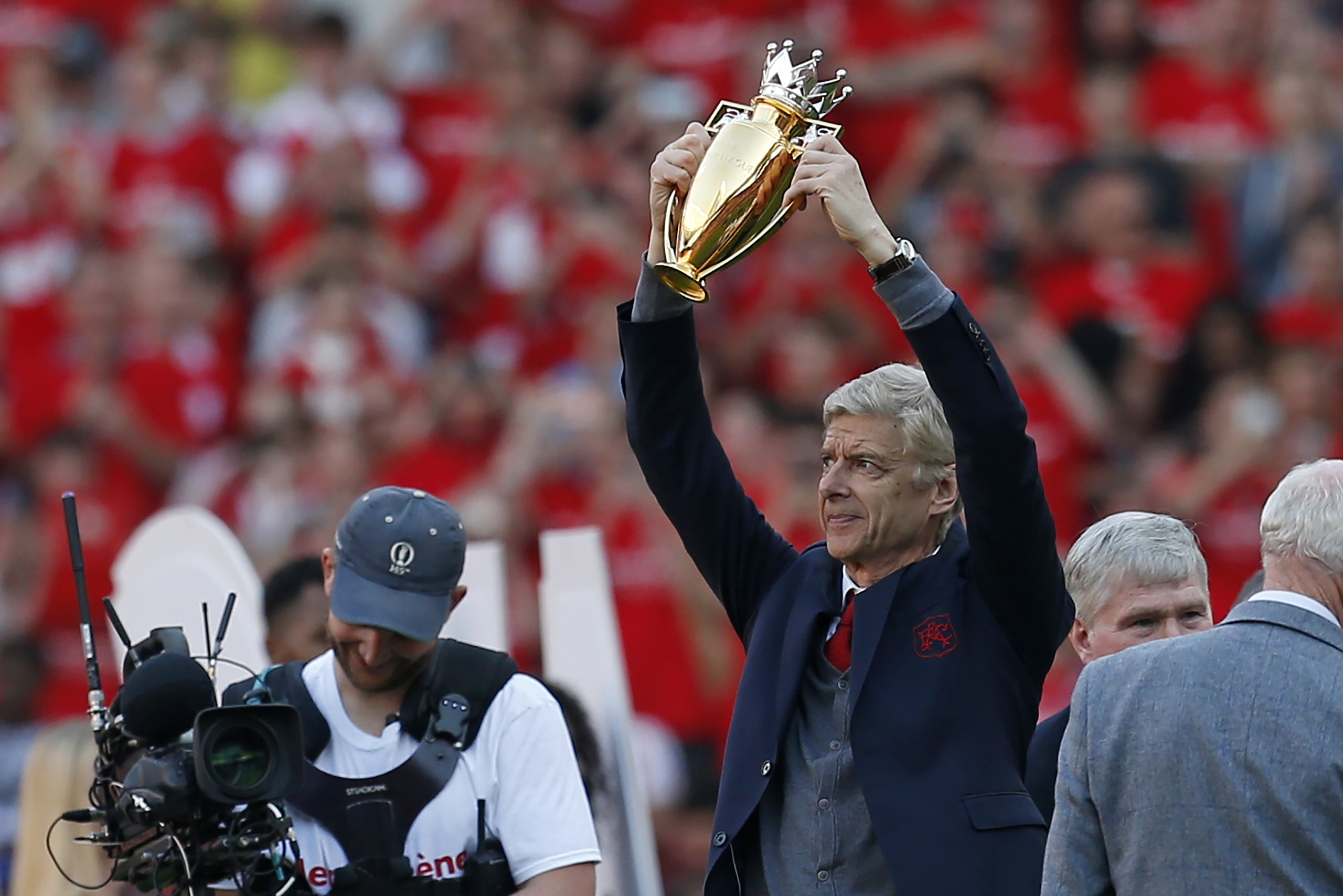 Arsenal's French manager Arsene Wenger holds up his gift of the 2003-4 gold Premier League trophy, awarded for their unbeaten season on the pitch after the English Premier League football match between Arsenal and Burnley at the Emirates Stadium in London