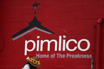 BALTIMORE, MD - MAY 20: A ran fan stands in front of a Pimlico sign prior to the 142nd running of the Preakness Stakes at Pimlico Race Course on May 20, 2017 in Baltimore, Maryland.  (Photo by Patrick Smith/Getty Images)