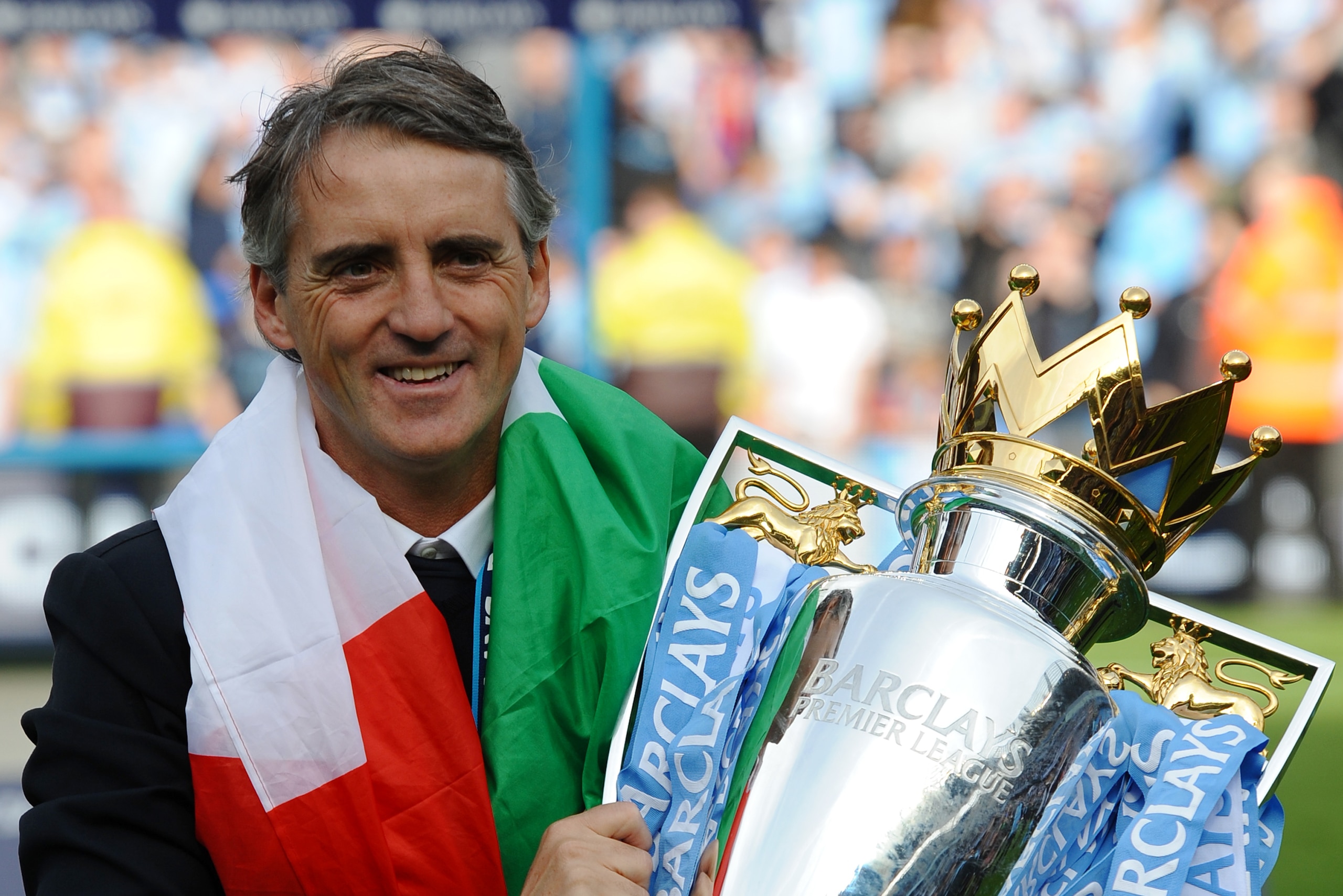 Manchester City's Italian manager Roberto Mancini celebrates on the pitch with the Premier League trophy after their 3-2 victory over Queens Park Rangers in the English Premier League football match between Manchester City and Queens Park Rangers at The E