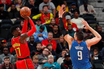 ATLANTA, GA - DECEMBER 09:  Dennis Schroder #17 of the Atlanta Hawks shoots against Nikola Vucevic #9 of the Orlando Magic to end the first half at Philips Arena on December 9, 2017 in Atlanta, Georgia.  NOTE TO USER: User expressly acknowledges and agree