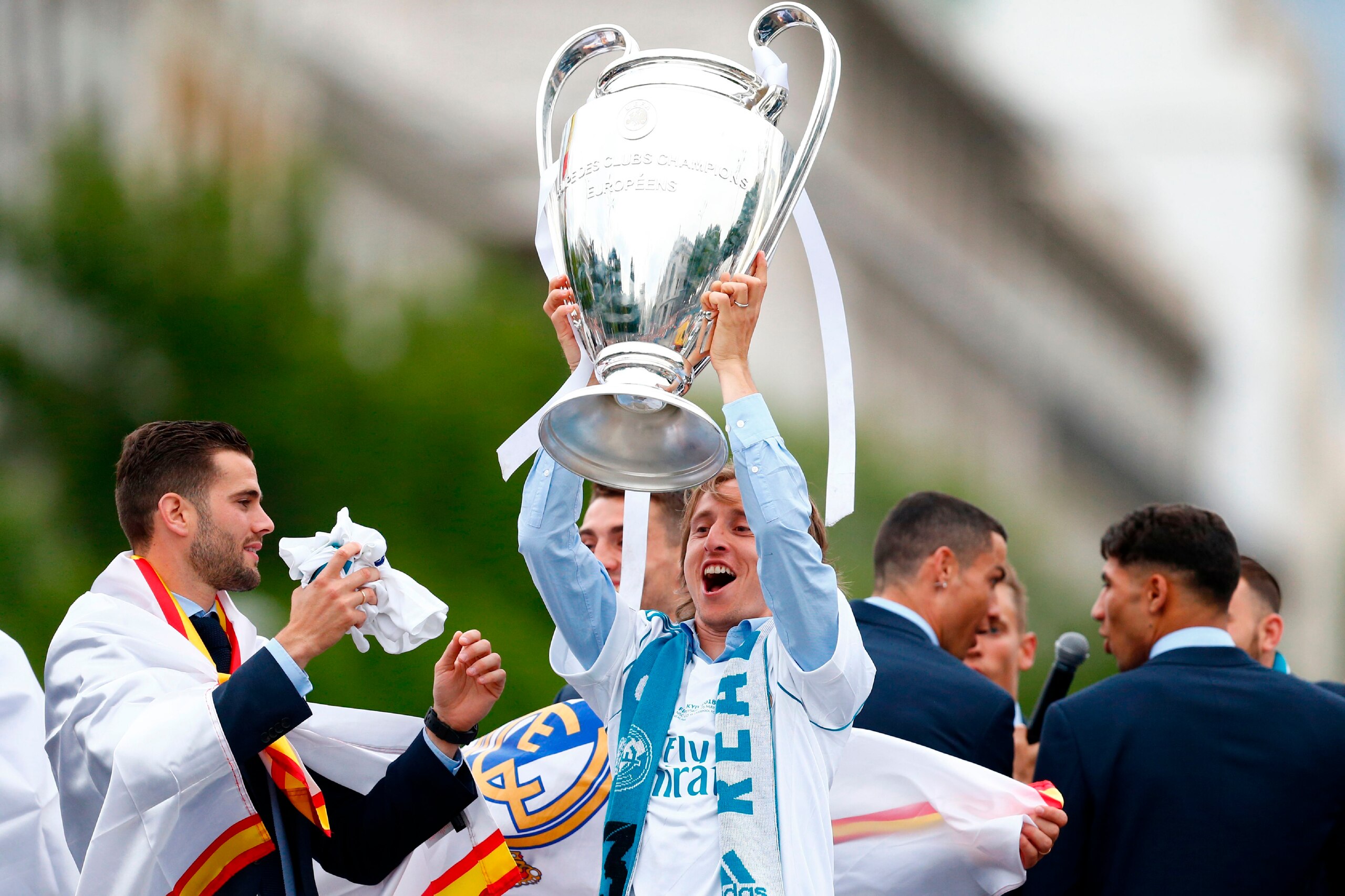 Real Madrid's Croatian midfielder Luka Modric (C) celebrates holding the trophy at Cibeles square in Madrid on May 27, 2018 after Real Madrid won their third Champions League title in a row in Kiev. (Photo by BENJAMIN CREMEL / AFP)        (Photo credit sh