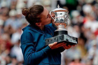 TOPSHOT - Romania's Simona Halep kisses her trophy, after winning the women's singles final match against Sloane Stephens of the US, on day fourteen of The Roland Garros 2018 French Open tennis tournament in Paris on June 9, 2018. (Photo by Thomas SAMSON 