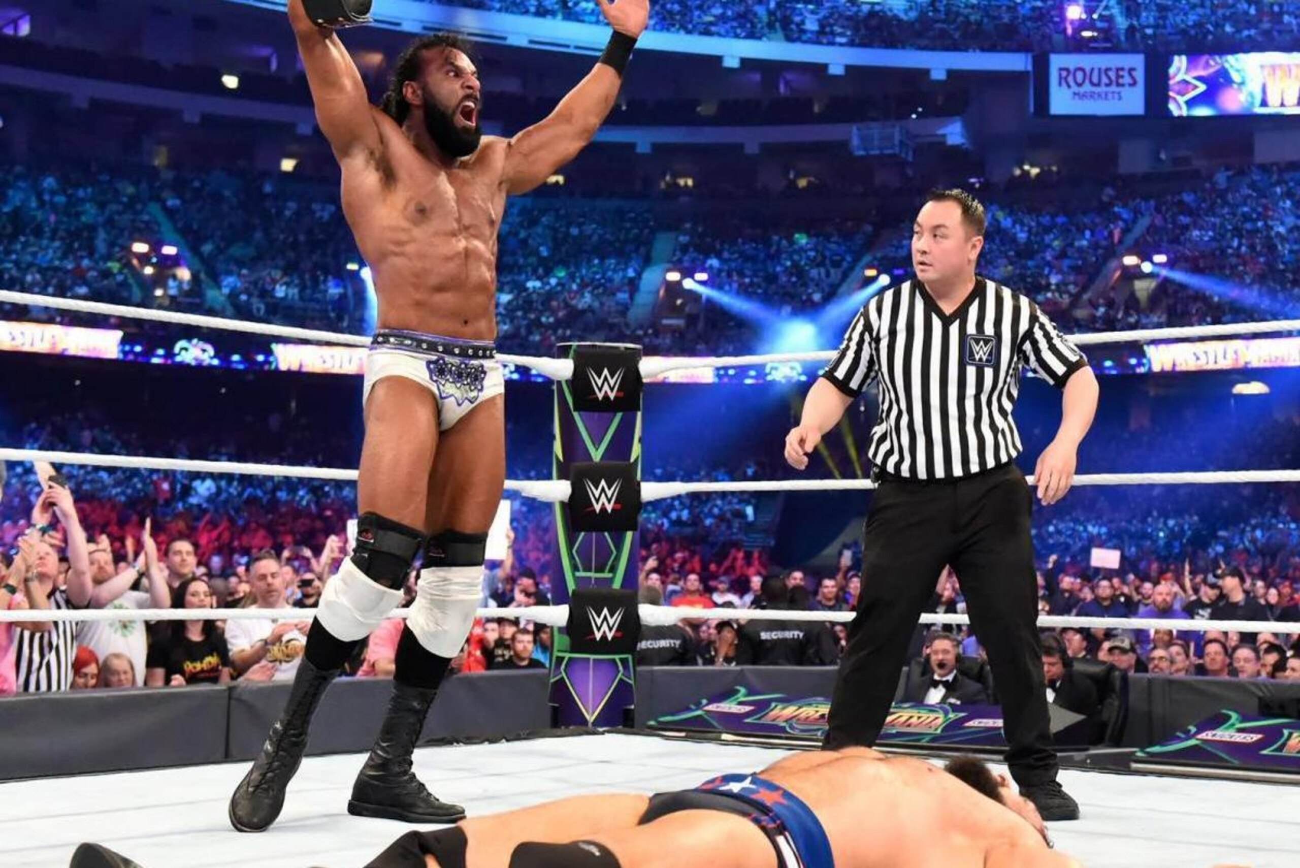 Jinder Mahal celebrates a WrestleMania win with a fallen Rusev at his feet.