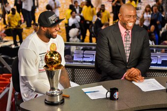 MIAMI, FL - JUNE 20: LeBron James #6 of the Miami Heat, sitting with the Bill Russell NBA Finals Most Valuable Player (MVP) trophy, is interviewed by NBA legend Magic Johnson following the Heat's victory against the San Antonio Spurs in Game Seven of the 