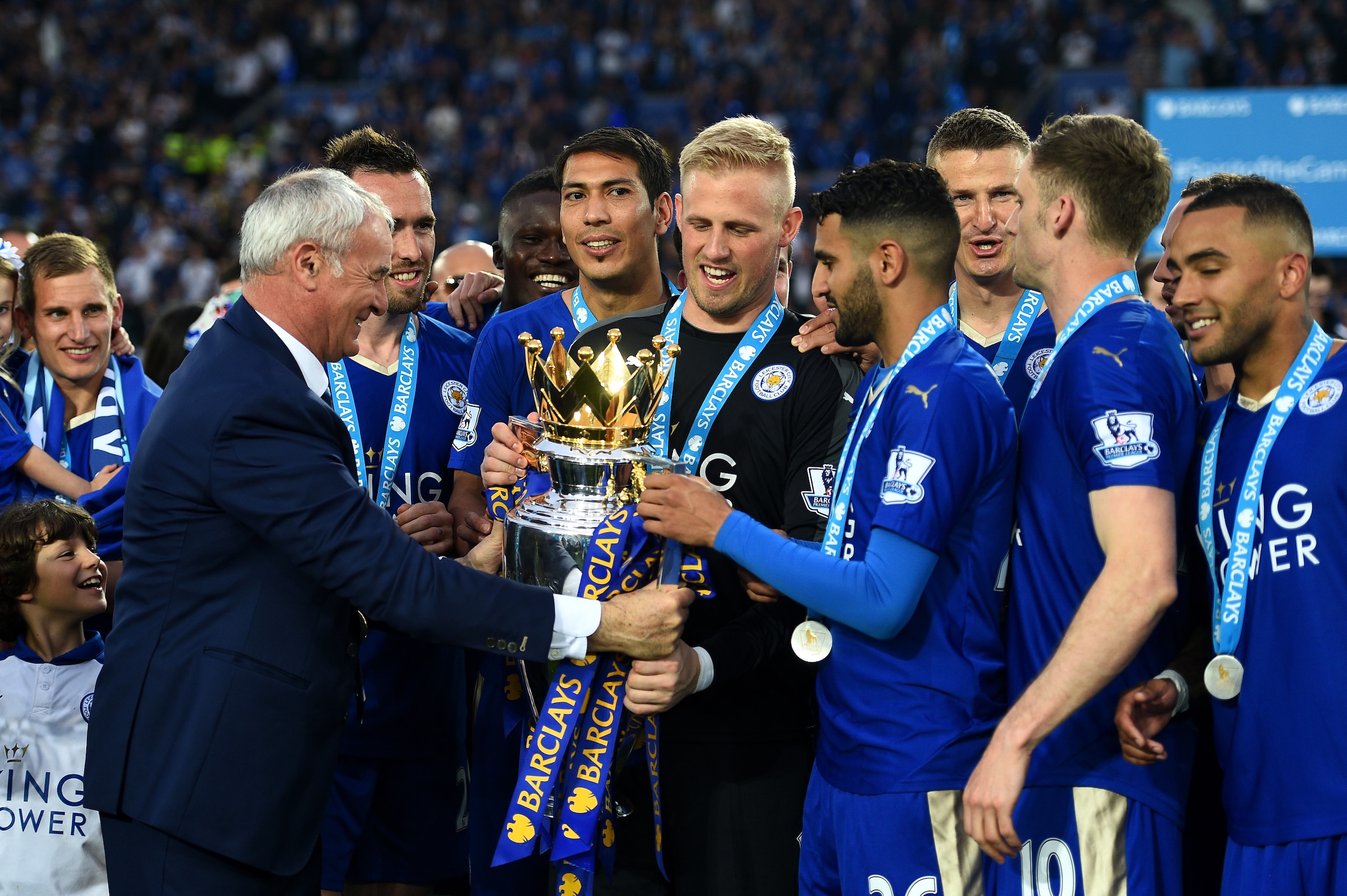 LEICESTER, ENGLAND - MAY 07:  Claudio Ranieri Manager of Leicester City passes the Premier League Trophy to Kasper Schmeichel and Riyad Mahrez as players and staffs celebrate the season champions after the Barclays Premier League match between Leicester C