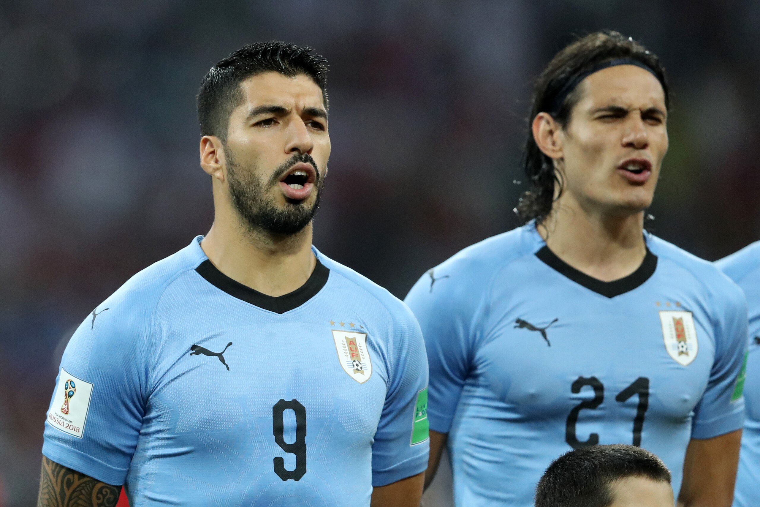SOCHI, RUSSIA - JUNE 30:  Luis Suarez of Uruguay and Edinson Cavani of Uruguay sing the national anthem prior to the 2018 FIFA World Cup Russia Round of 16 match between Uruguay and Portugal at Fisht Stadium on June 30, 2018 in Sochi, Russia.  (Photo by F
