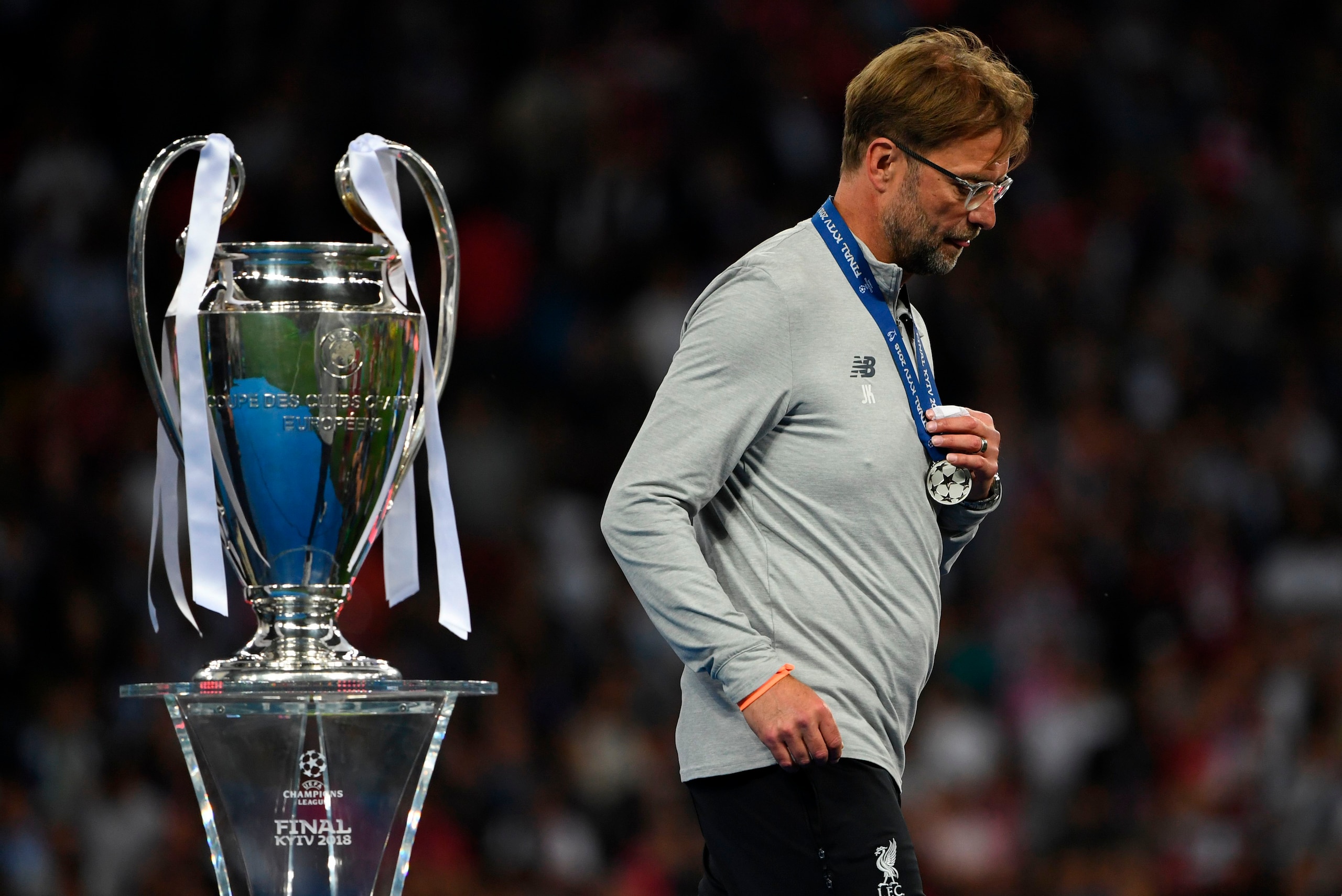 TOPSHOT - Liverpool's German manager Jurgen Klopp walks past the trophy as he collects his loser's medal after the UEFA Champions League final football match between Liverpool and Real Madrid at the Olympic Stadium in Kiev, Ukraine on May 26, 2018. - Real