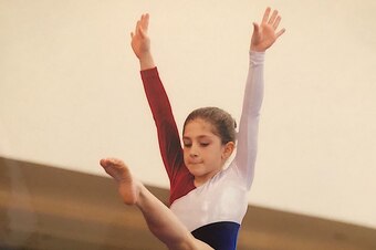 Brennan, 12, competes on the balance beam during a regional event at level 8.
