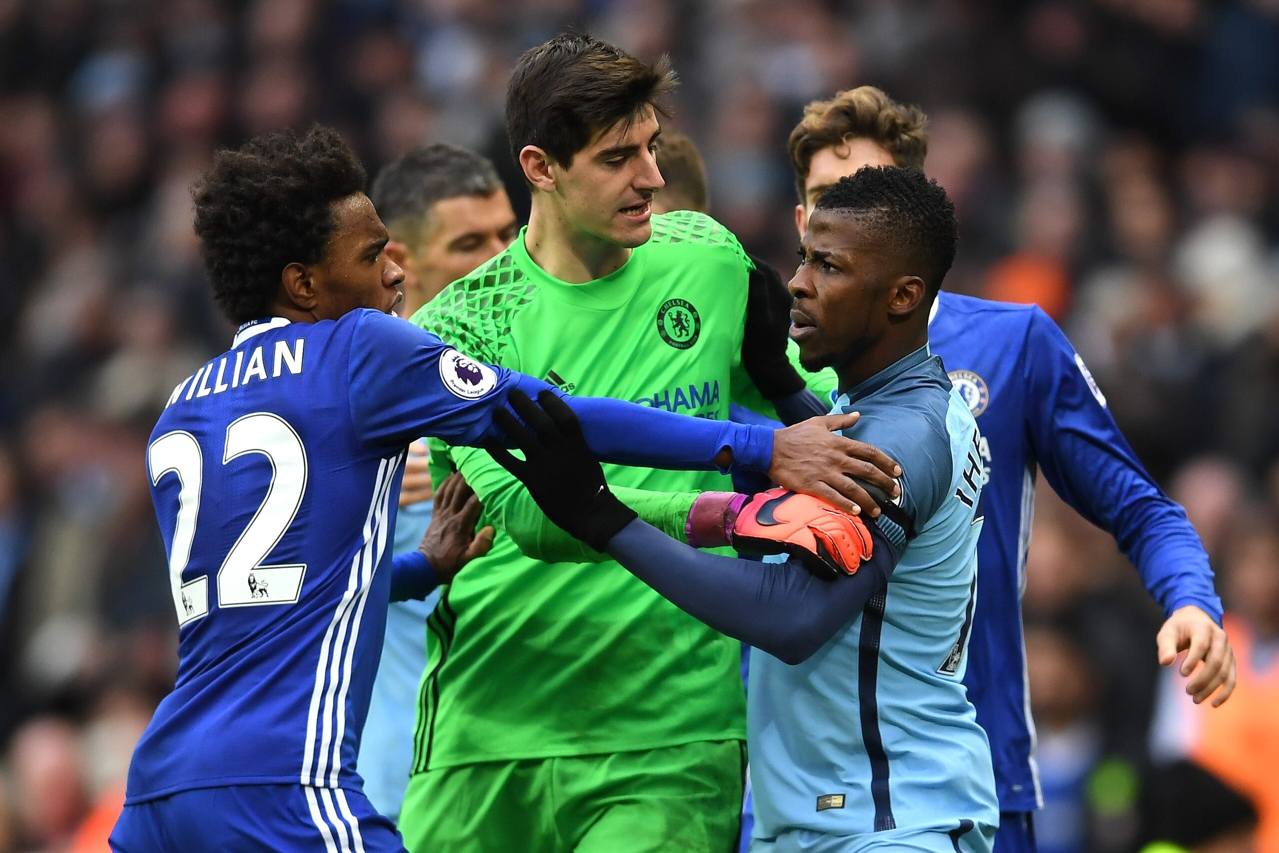 MANCHESTER, ENGLAND - DECEMBER 03: Kelechi Iheanacho of Manchester City and Willian of Chelsea square off while Thibaut Courtois of Chelsea tries to separate them after David Luiz of Chelsea is fouled by Sergio Aguero of Manchester City during the Premier