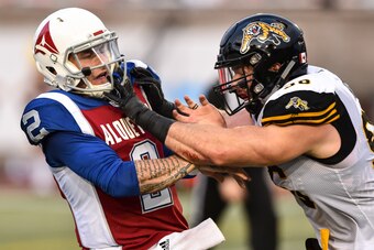 MONTREAL, QC - AUGUST 03:  Defensive end Jason Neill #96 of the Hamilton Tiger-Cats (R) defends against quarterback Johnny Manziel #2 of the Montreal Alouettes (L) during the CFL game at Percival Molson Stadium on August 3, 2018 in Montreal, Quebec, Canad