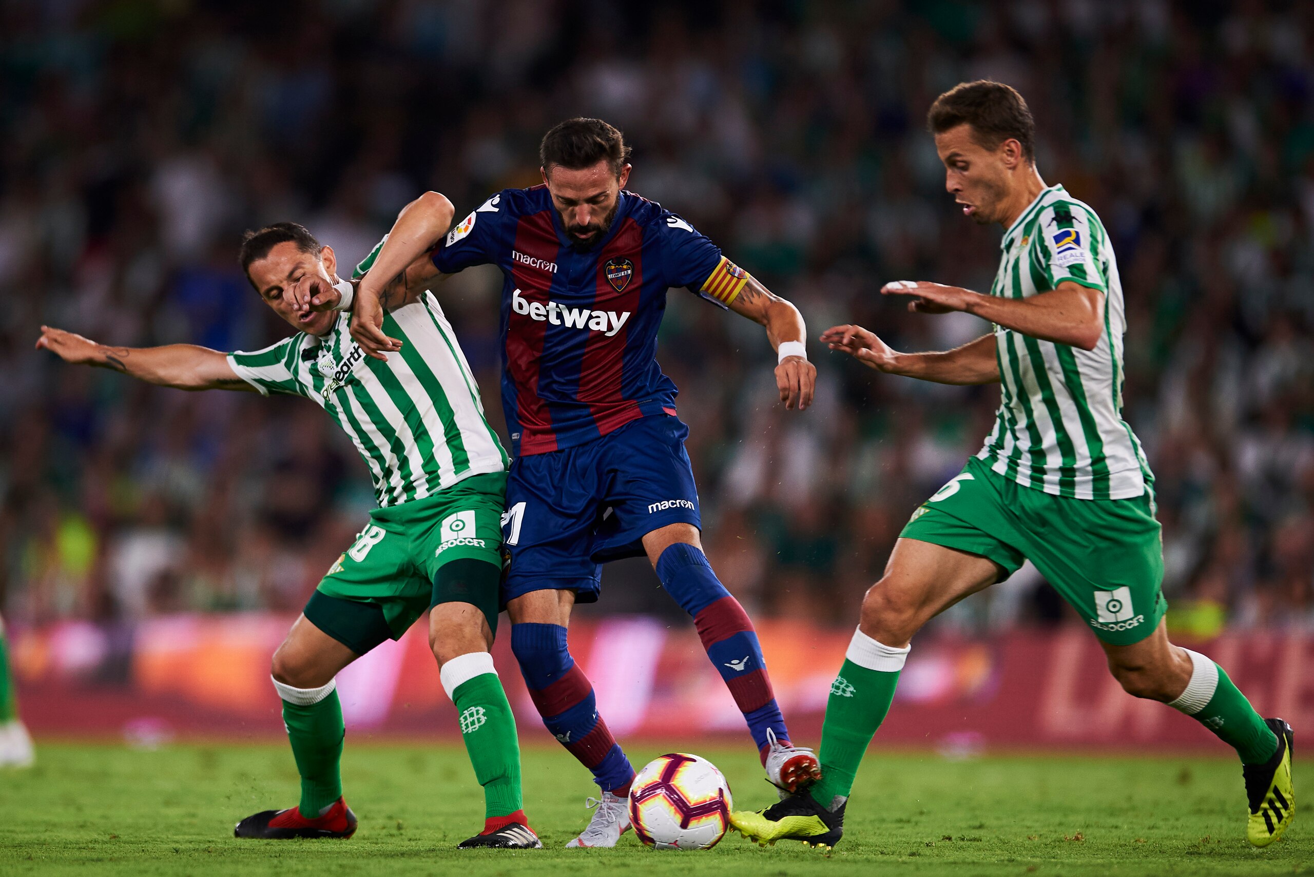 SEVILLE, SPAIN - AUGUST 17: Andres Guardado and Sergio Canales of Real Betis compete for the ball with Jose Luis Morales of Levante UD during the La Liga match between Real Betis Balompie and Levante UD at Estadio Benito Villamarin on August 17, 2018 in S