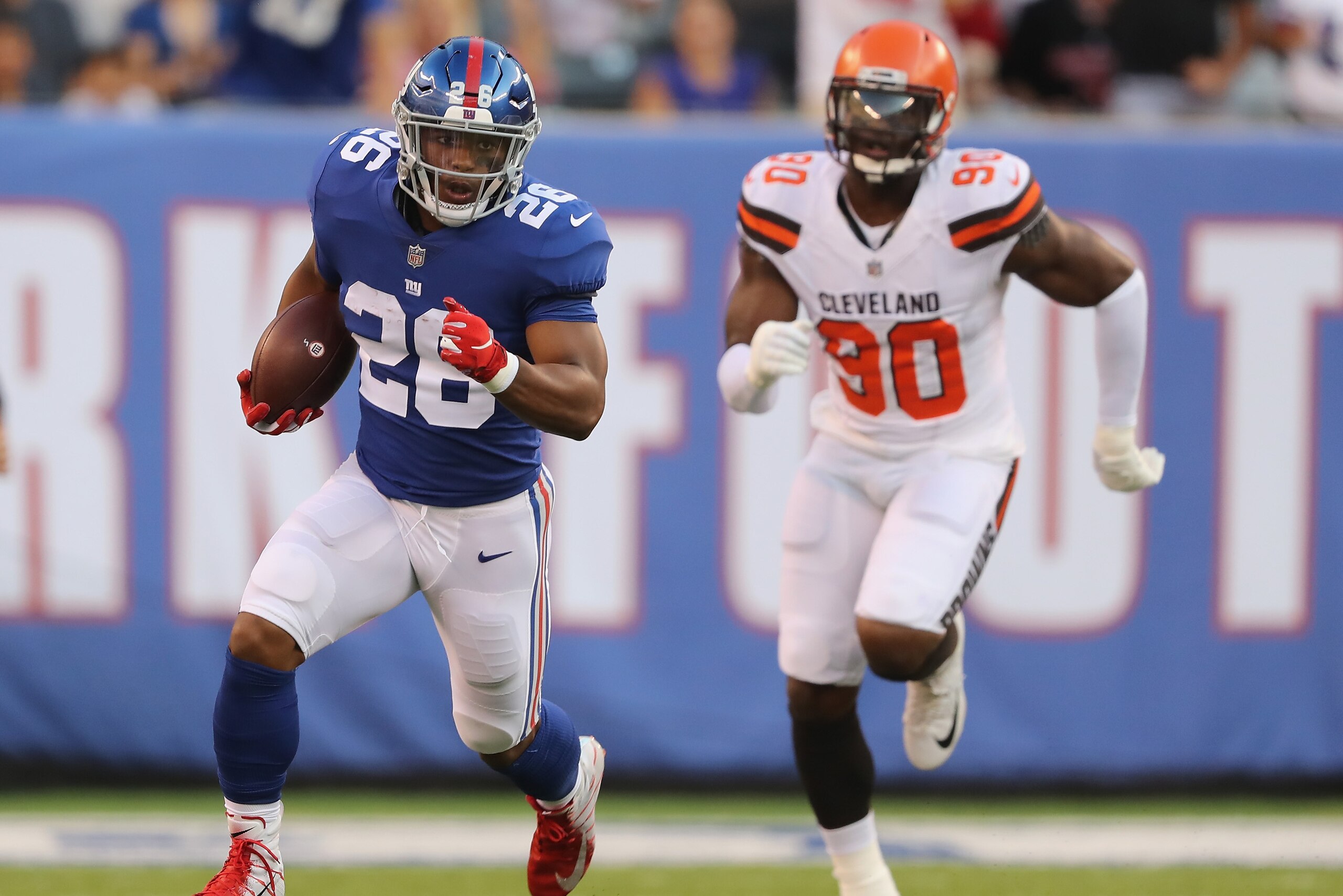 EAST RUTHERFORD, NJ - AUGUST 09:  Saquon Barkley #26 of the New York Giants carries the ball as Emmanuel Ogbah #90 of the Cleveland Browns in the first quarter during their preseason game on August 9,2018 at MetLife Stadium in East Rutherford, New Jersey.