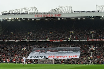 A banner that reads 'we'll never die' travels across the Stretford End in comemmoration of the 1958 Munich Air Disaster in the 60th anniversary year of the crash that killed 23 during the English Premier League football match between Manchester United and