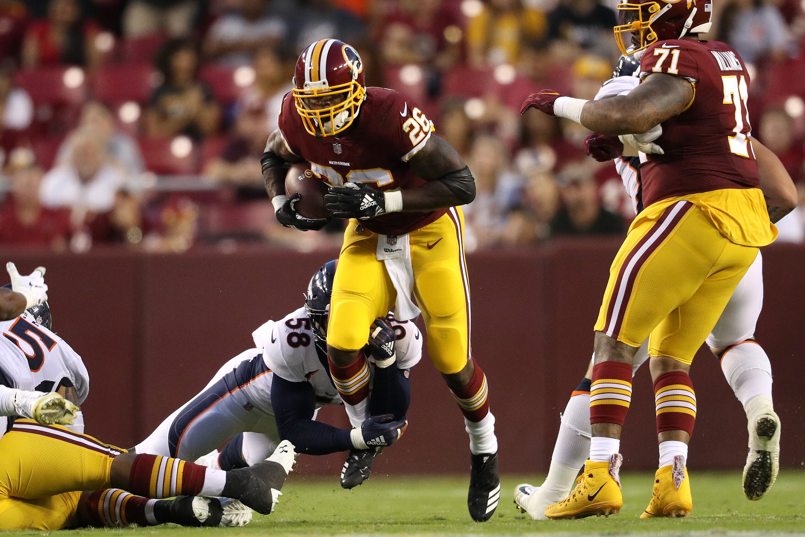 LANDOVER, MD - AUGUST 24: Running back Adrian Peterson #26 of the Washington Redskins rushes past linebacker Von Miller #58 of the Denver Broncos in the first quarter during a preseason game at FedExField on August 24, 2018 in Landover, Maryland. (Photo b