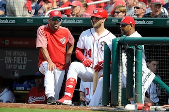 WASHINGTON, DC - AUGUST 05:  Bryce Harper #34 of the Washington Nationals talks with hitting coach Kevin Long #54 and manager Dave Martinez #4 during a pitching change in the eighth inning against the Cincinnati Reds at Nationals Park on August 5, 2018 in