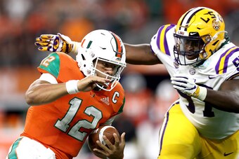 ARLINGTON, TX - SEPTEMBER 02:  Malik Rosier #12 of the Miami Hurricanes runs the ball against Glen Logan #97 of the LSU Tigers in the first quarter during the AdvoCare Classic at AT&T Stadium on September 2, 2018 in Arlington, Texas.  (Photo by Ronald Mar