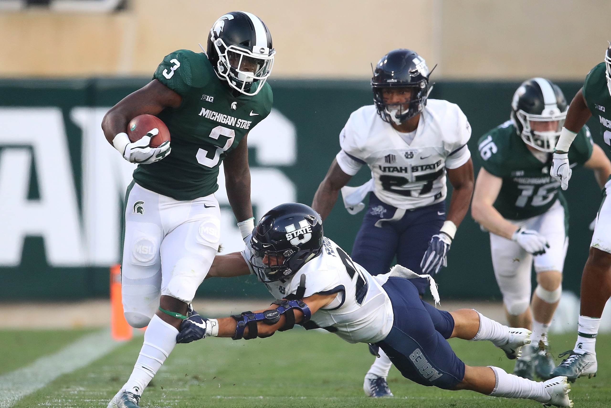 EAST LANSING, MI - AUGUST 31: LJ Scott #3 of the Michigan State Spartans tries to run through the tackle of  Gaje Ferguson #23 of the Utah State Aggies at Spartan Stadium on August 31, 2018 in East Lansing, Michigan. (Photo by Gregory Shamus/Getty Images)