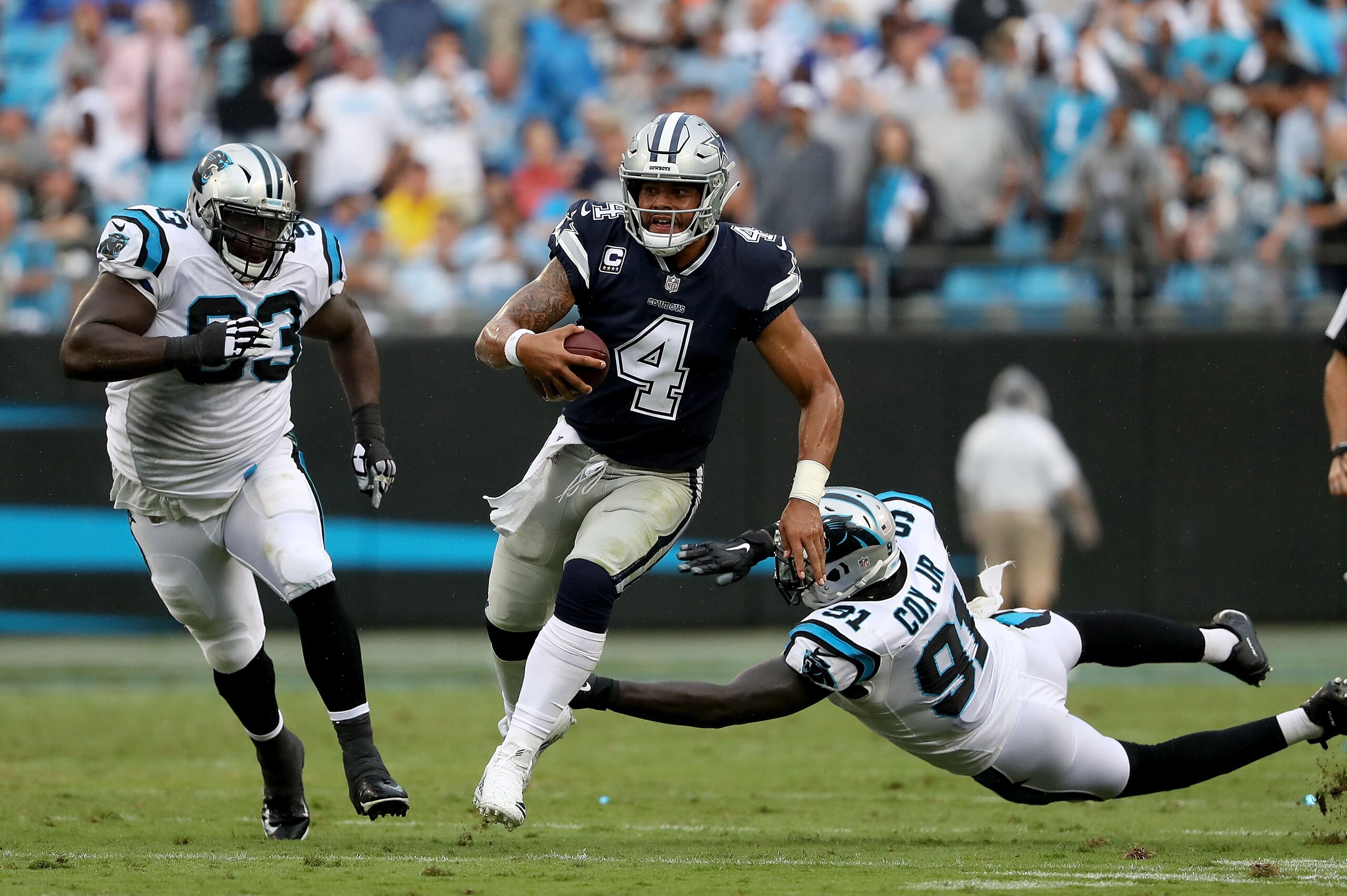 CHARLOTTE, NC - SEPTEMBER 09: Dak Prescott #4 of the Dallas Cowboys runs the ball against Brendan Mahon #63 and Bryan Cox #91 of the Carolina Panthers in the third quarter during their game at Bank of America Stadium on September 9, 2018 in Charlotte, No CHARLOTTE, NC - SEPTEMBER 09: Dak Prescott #4 of the Dallas Cowboys runs the ball against Brendan Mahon #63 and Bryan Cox #91 of the Carolina Panthers in the third quarter during their game at Bank of America Stadium on September 9, 2018 in Charlotte, No