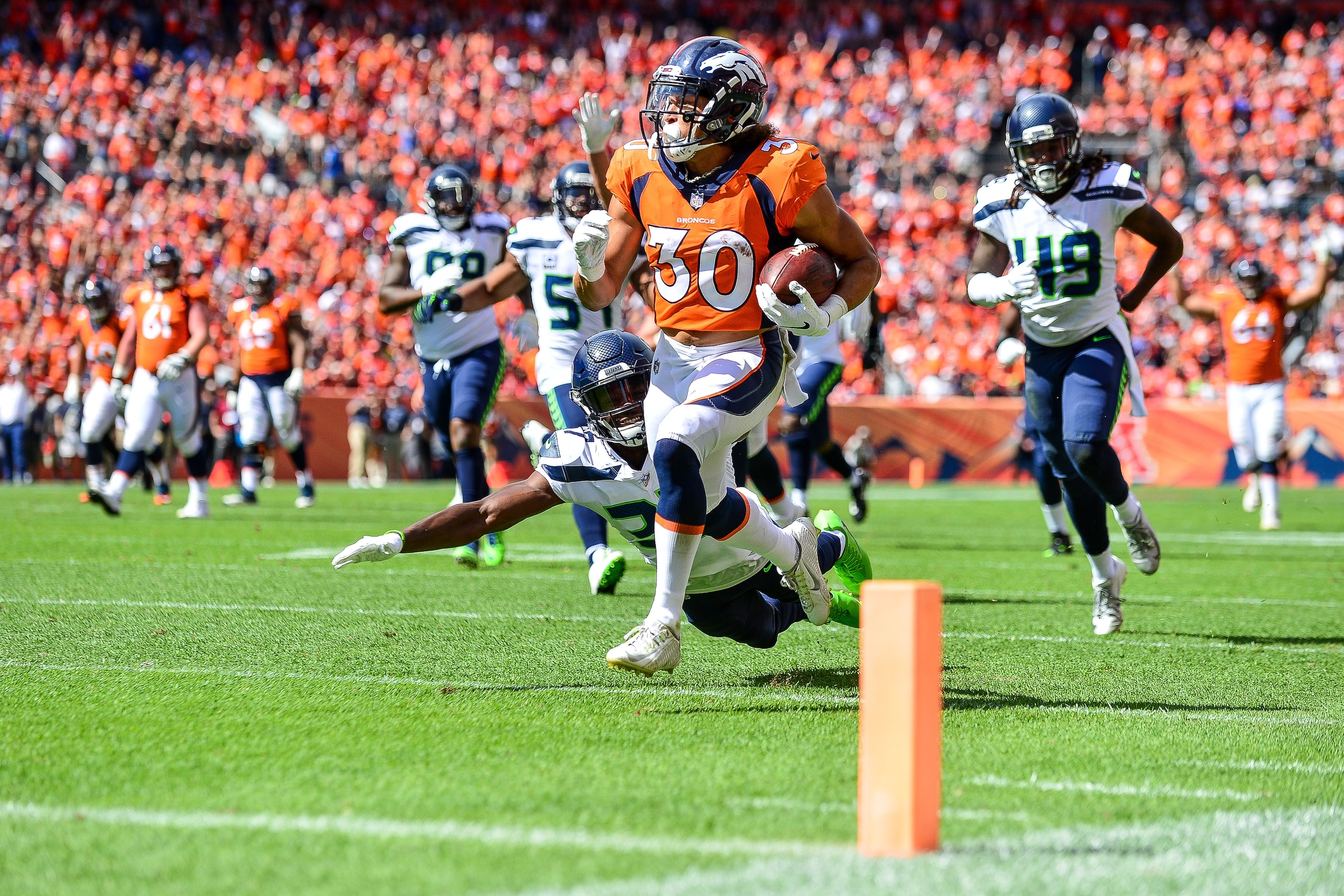 DENVER, CO - SEPTEMBER 9: Running back Phillip Lindsay #30 of the Denver Broncos of the Denver Broncos scores a first quarter touchdown on a reception as cornerback Tre Flowers #37 of the Seattle Seahawks falls to the ground during a game at Broncos Stad DENVER, CO - SEPTEMBER 9: Running back Phillip Lindsay #30 of the Denver Broncos of the Denver Broncos scores a first quarter touchdown on a reception as cornerback Tre Flowers #37 of the Seattle Seahawks falls to the ground during a game at Broncos Stad